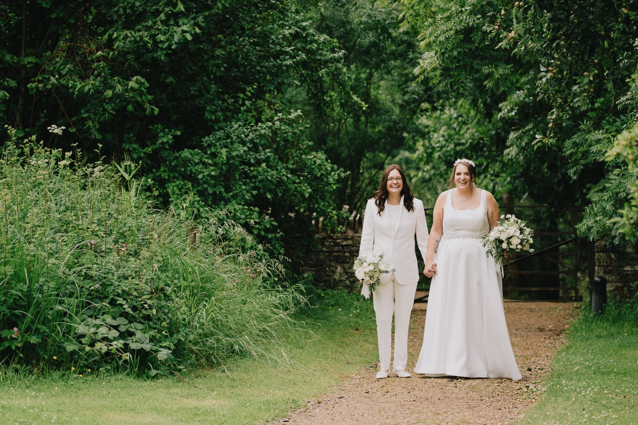 Two brides walking up path to Folly Farm wedding venue after getting married