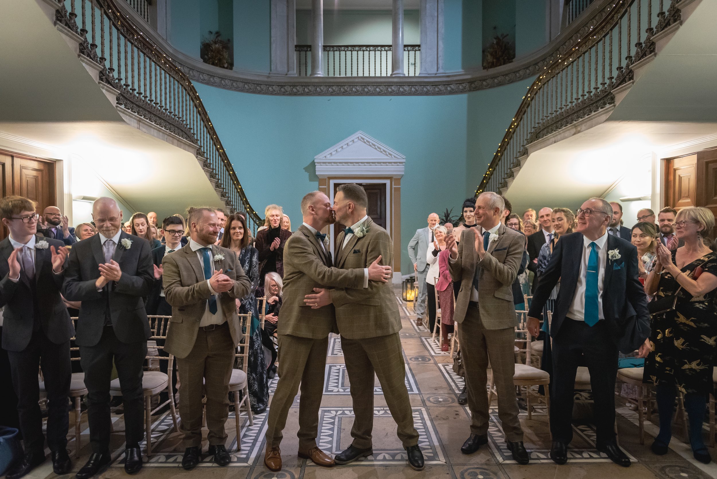 2 grooms kiss after sealing their wedding at Leigh Court in Bristol