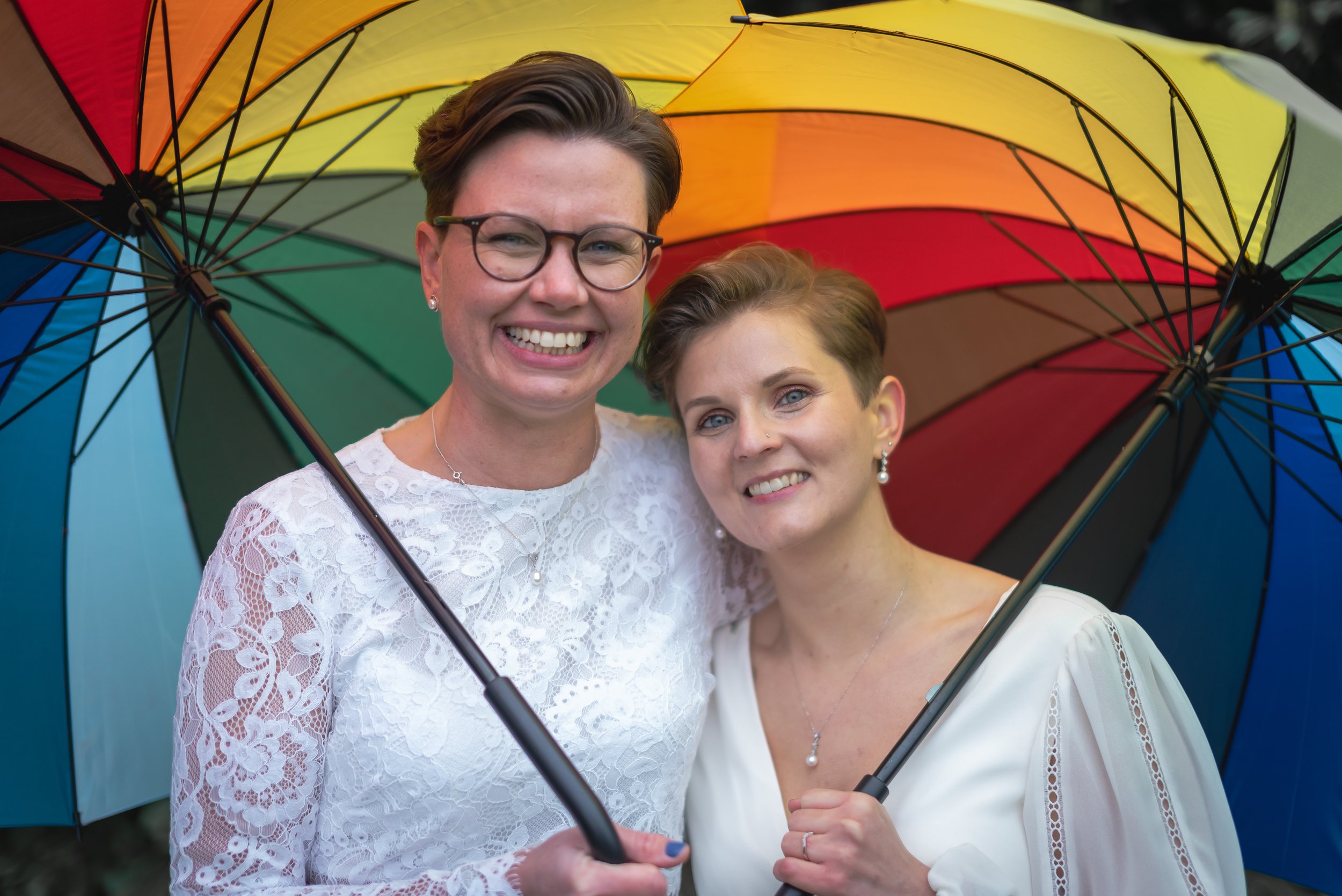 2 brides at The Manor House in Moreton after getting married. Proudly holding a rainbow umbrella