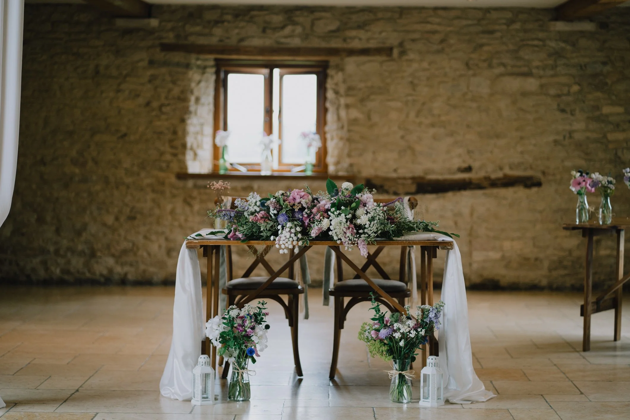Floral arrangement decorating the table at the top of the wedding ceremony aisle at Kingscote Barn
