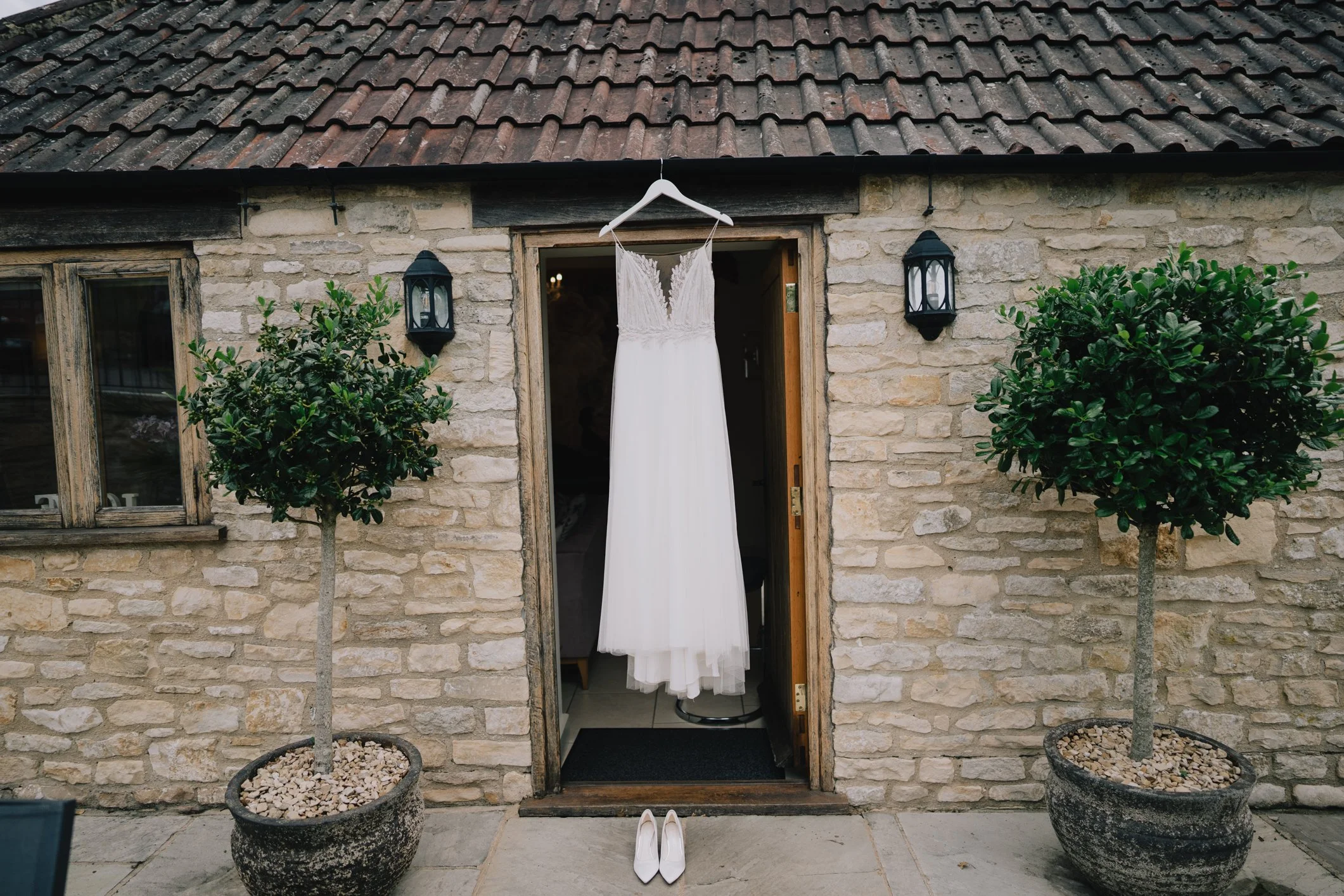 Wedding dress hanging outside the bridal prep room at Kingscote Barn, catching the natural morning light