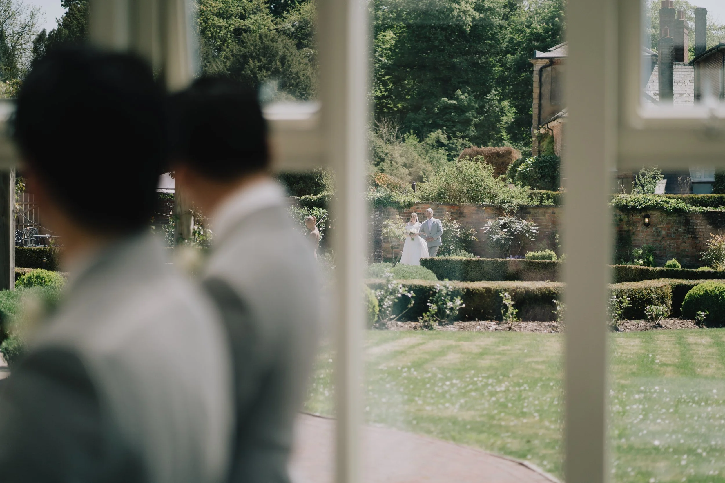 Bride Lucy walking through Syrencot’s walled garden with her father en route to the ceremony