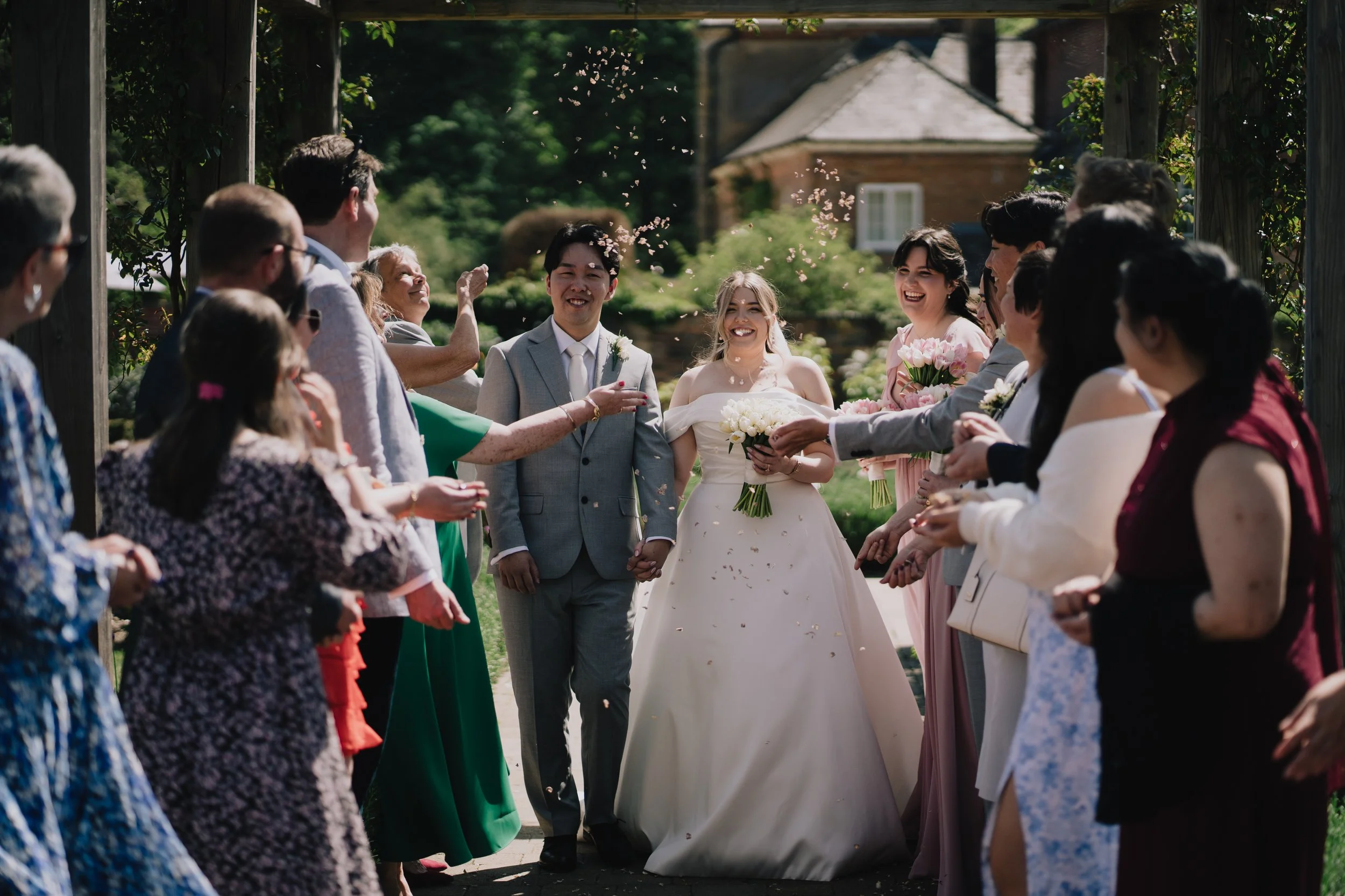 Guests throwing confetti over Lucy and Kevin outside the Glasshouse at Syrencot
