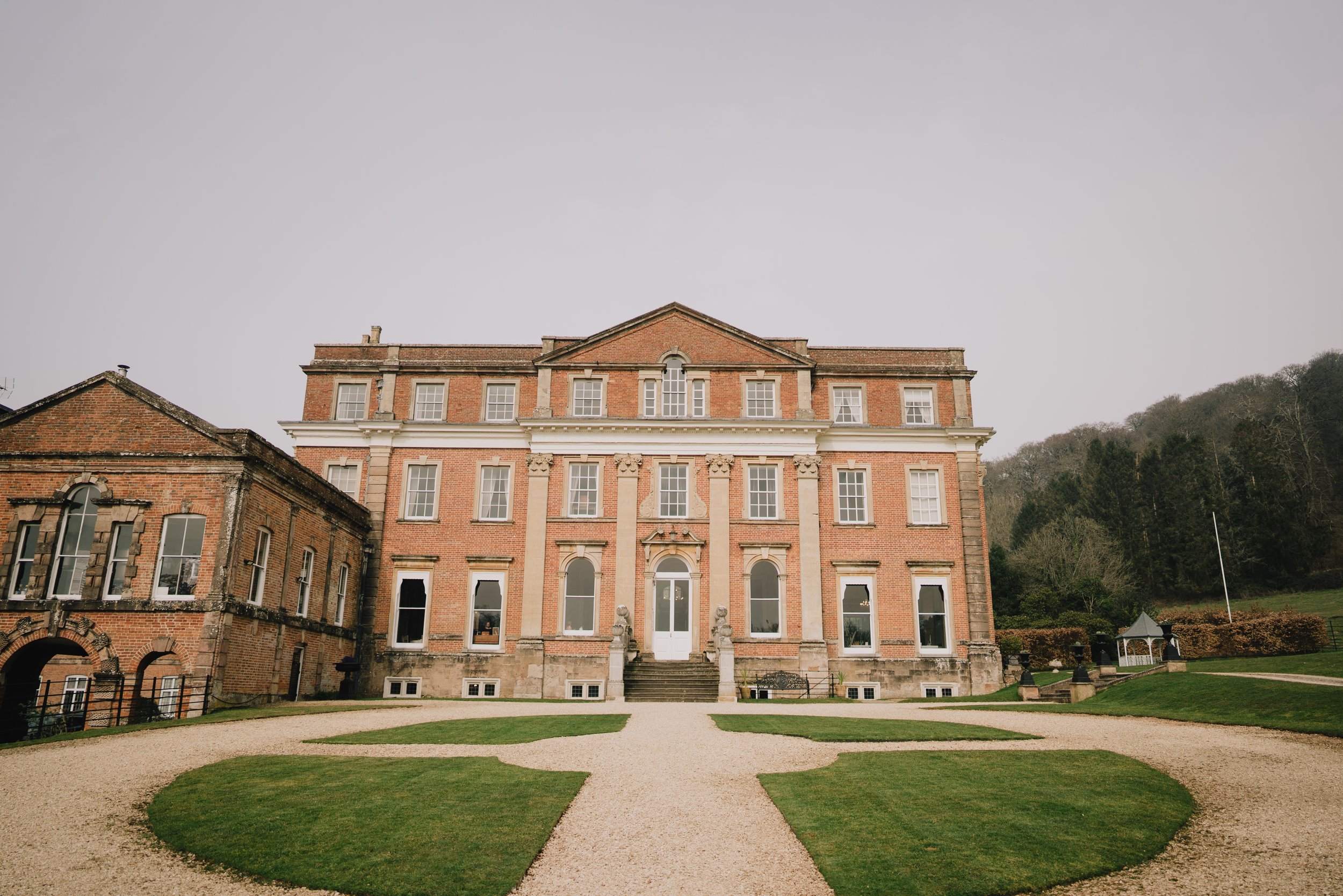 Elegant exterior of Crowcombe Court wedding venue in Somerset, Georgian architecture surrounded by landscaped gardens.