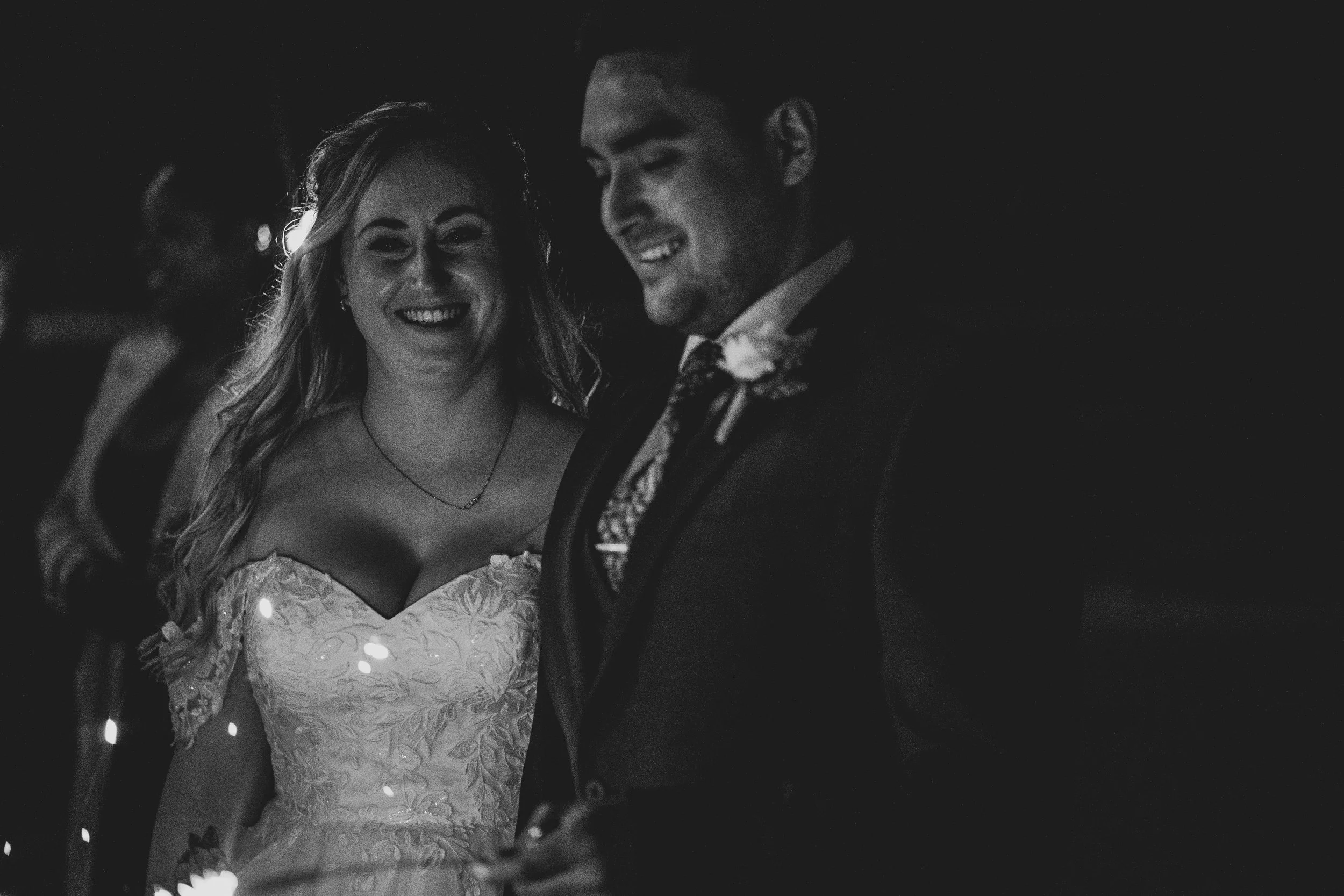 Black and white photo of bride and groom holding sparklers during evening celebrations at Crowcombe Court wedding.