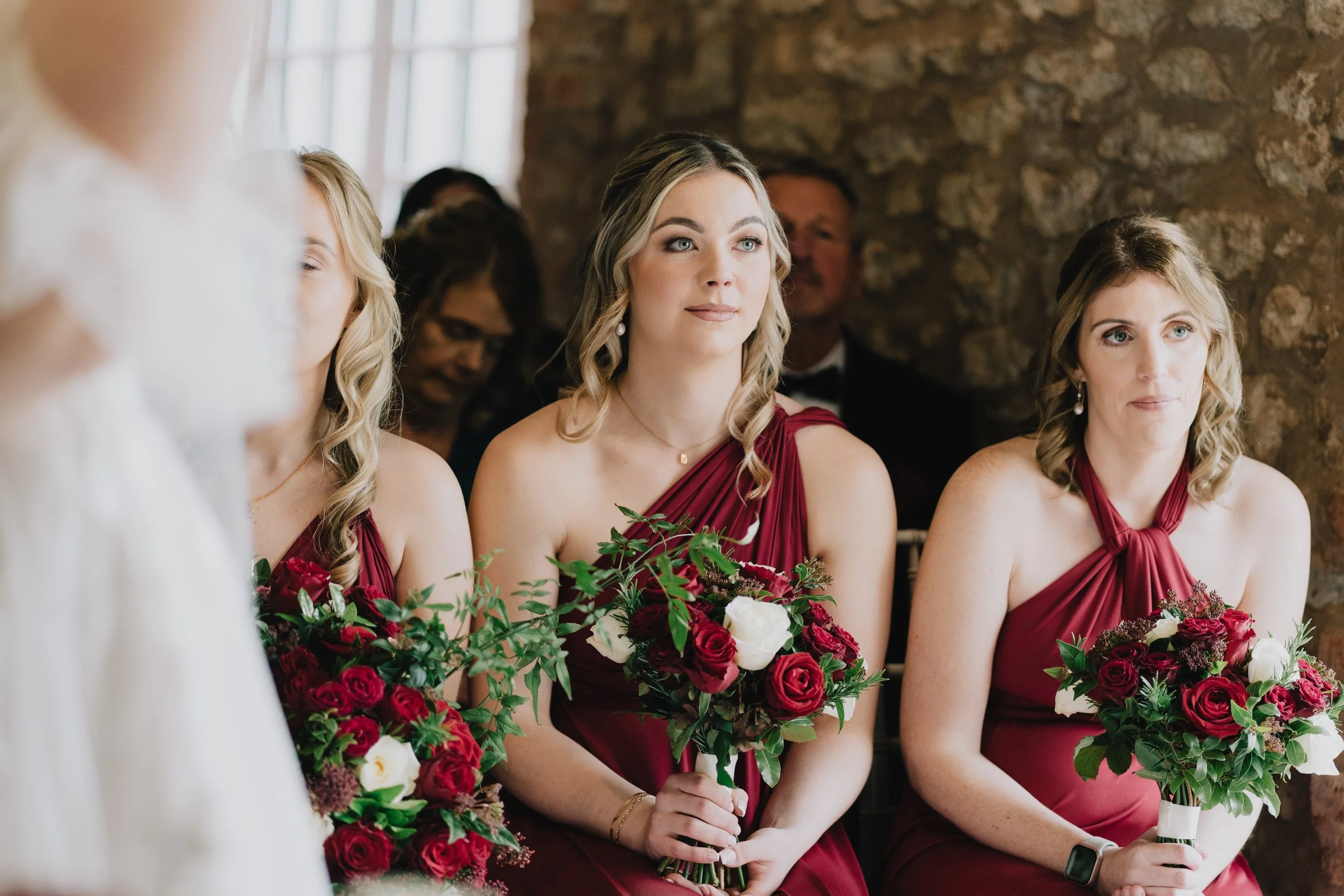 Bridesmaid in red dress holding flowers at Christmas wedding at Quantock Lakes