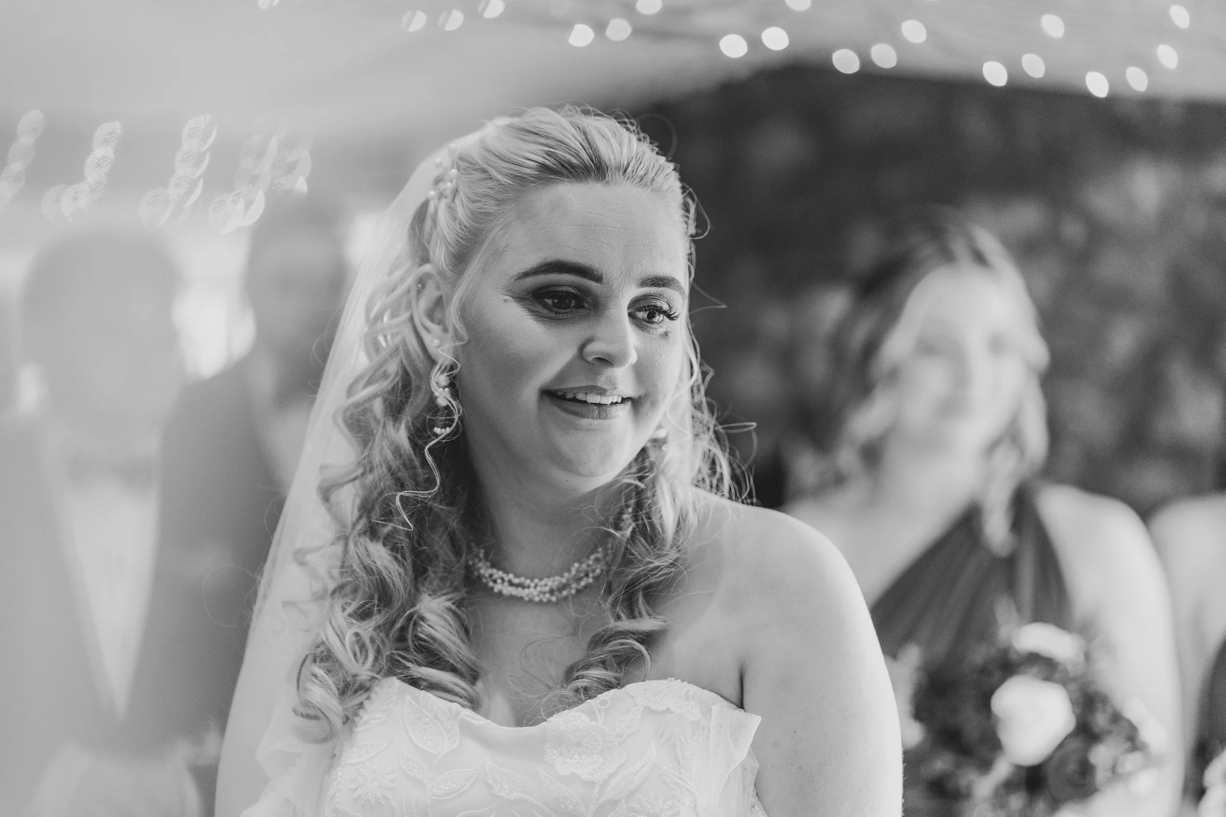 Black and white photo of bride standing at the end of the aisle during emotional winter wedding ceremony at Quantock Lakes.