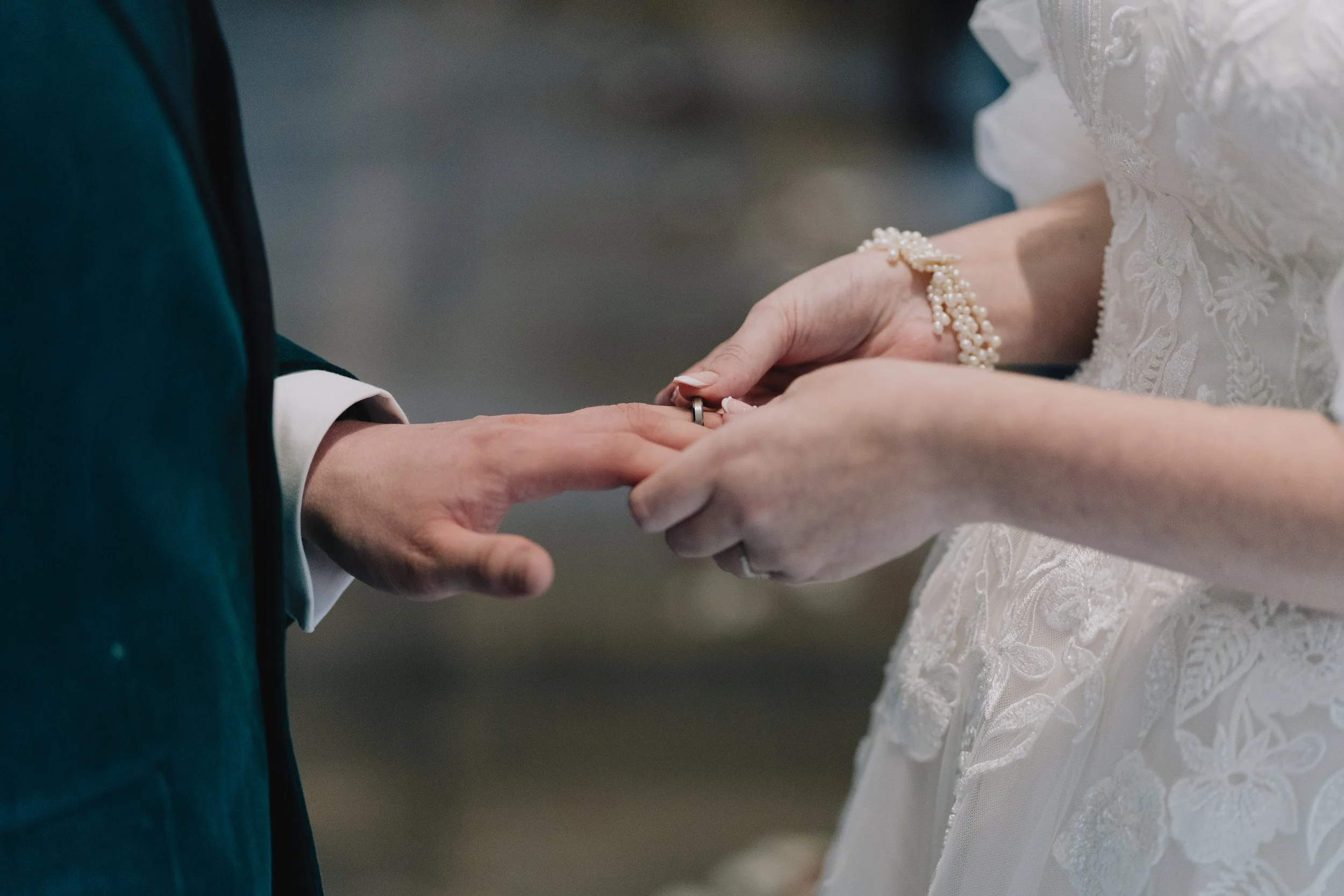 Bride placing wedding ring on groom’s finger during ceremony at Quantock Lakes, captured in a heartfelt moment.