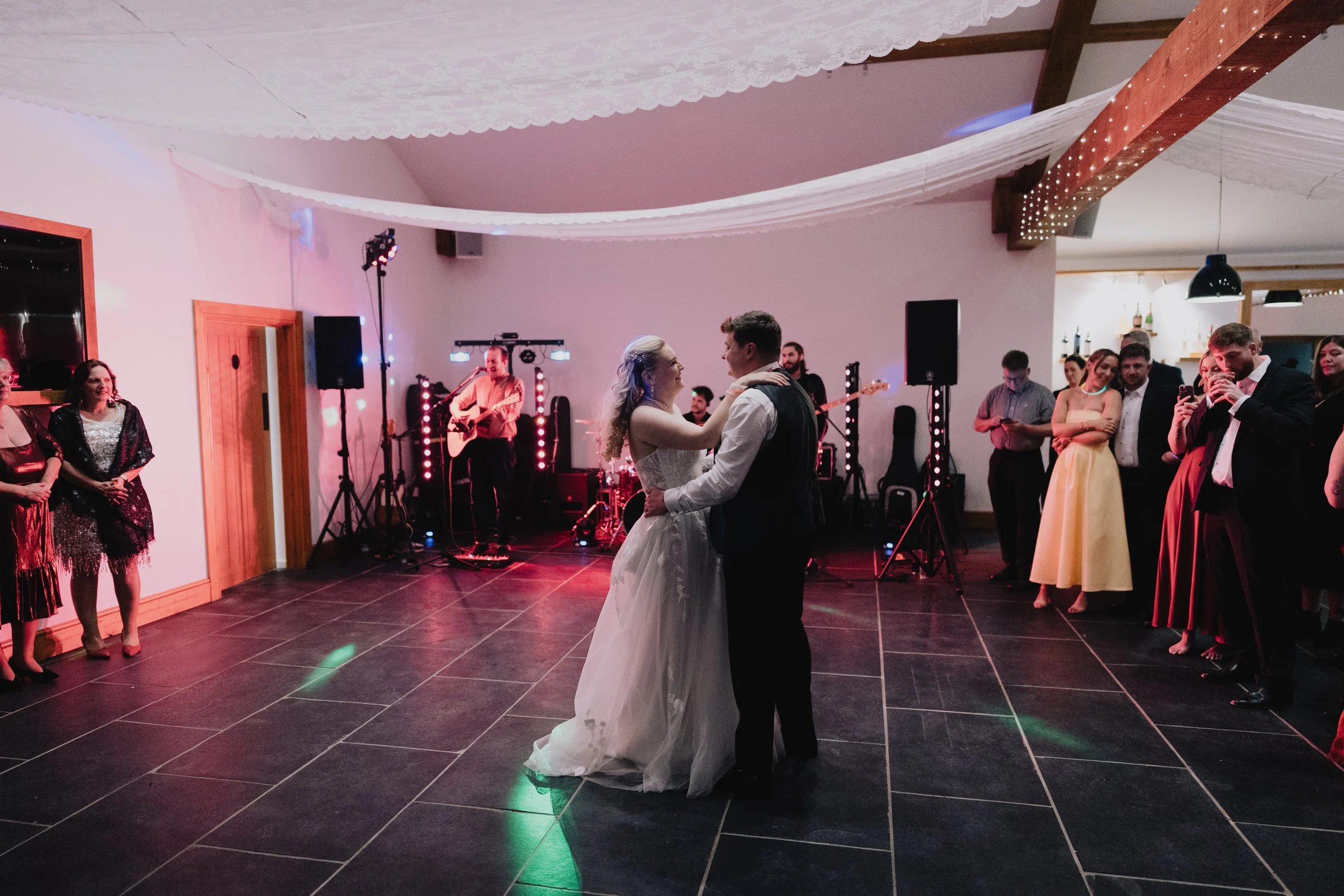 Bride and groom sharing their first dance under warm lighting during evening reception at Quantock Lakes wedding.