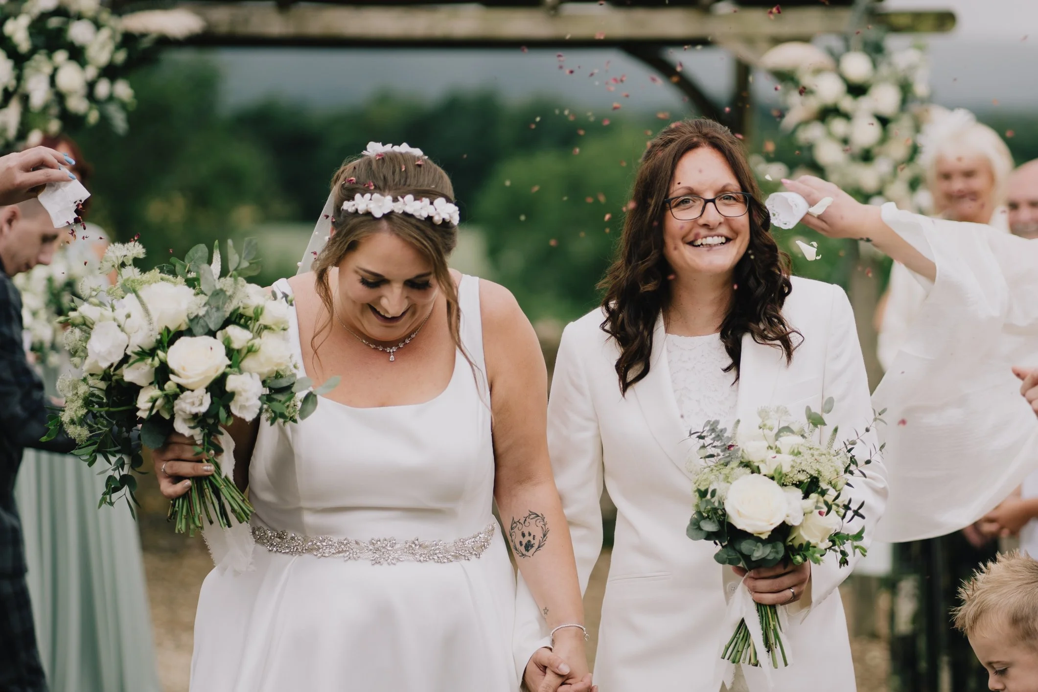 Two brides being covered in confetti on their wedding day at Folly Farm