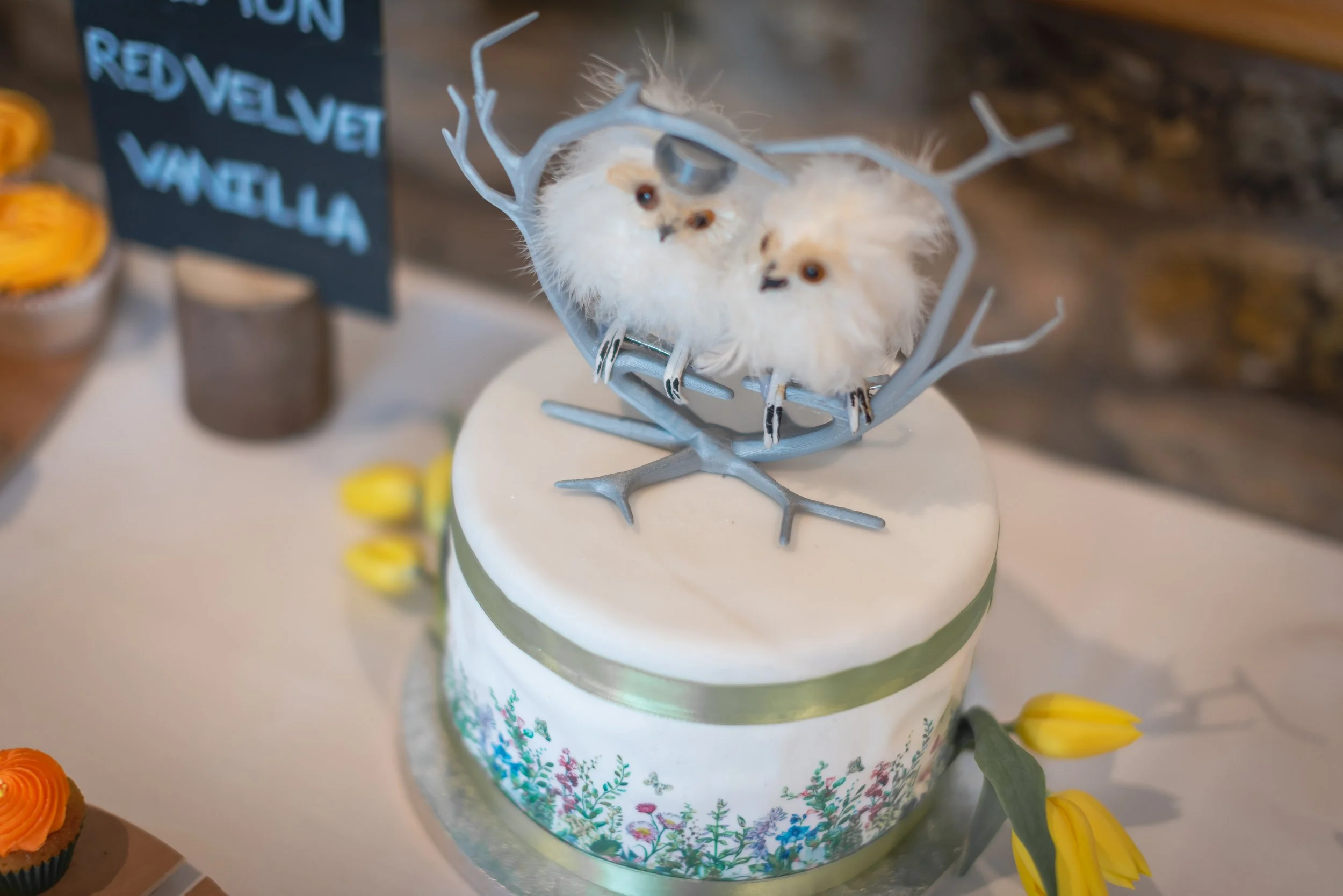 Enchanted white cake with a snowflake design, topped with a reindeer with cotton ball fur and small animal faces, and decorated with yellow flowers to match the brides love of birds.