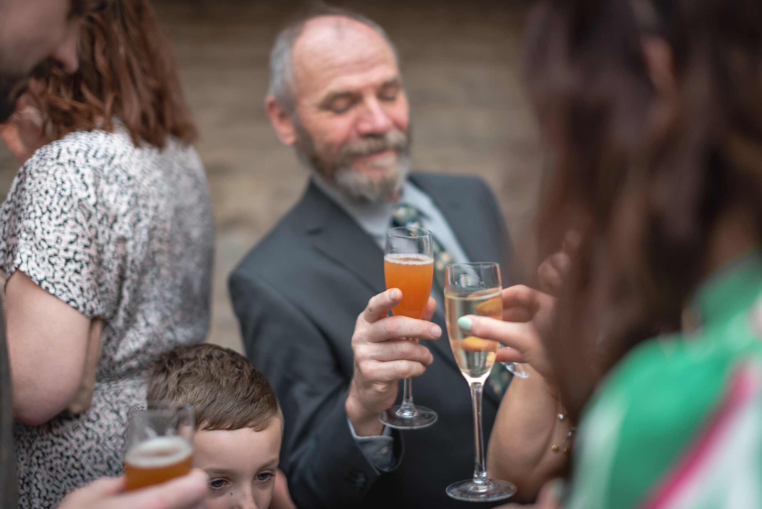 Group of people raising glasses filled with champagne and orange cocktail at wedding reception