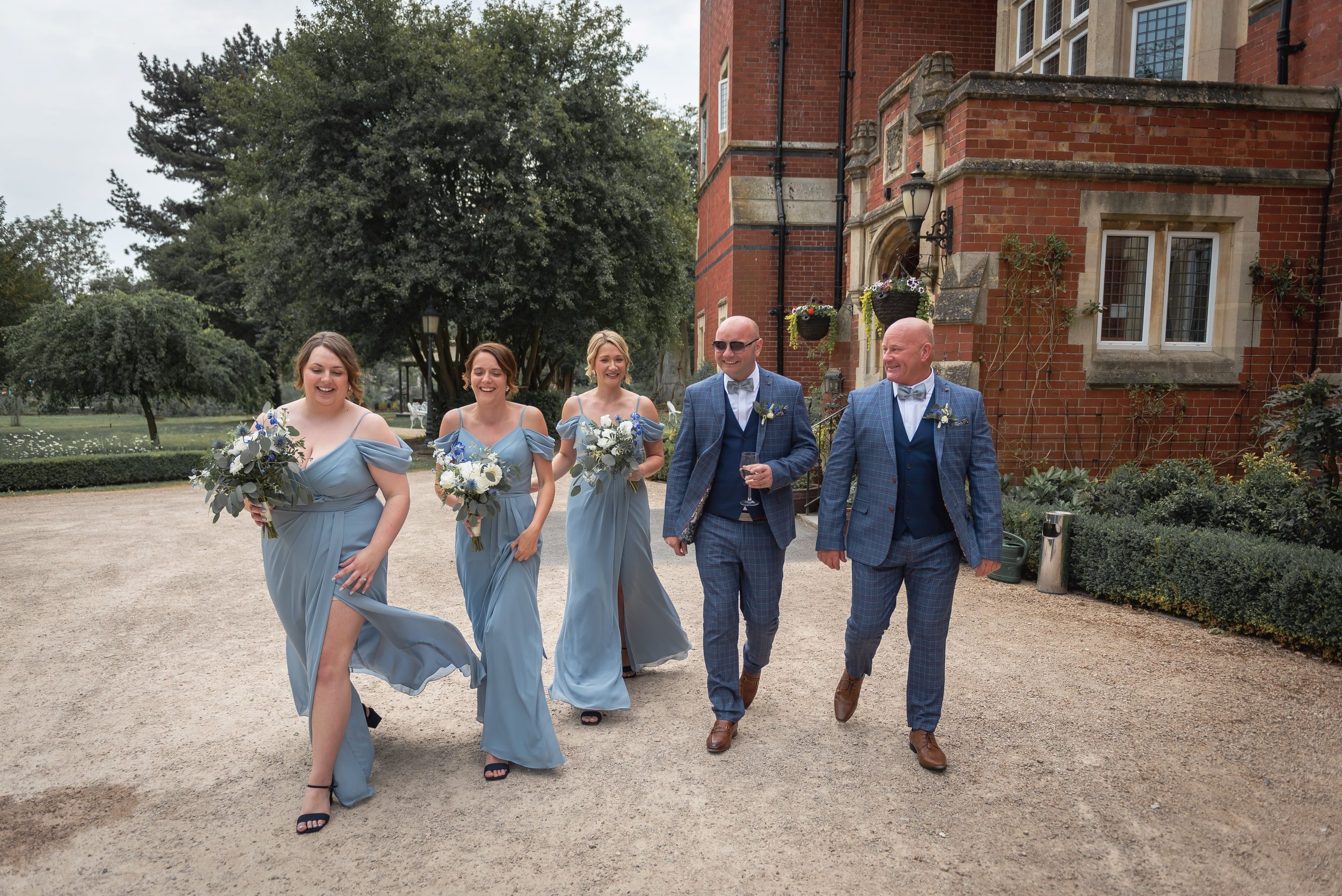 Bridesmaids and two grooms walking over the ceremony at Berwick Lodge