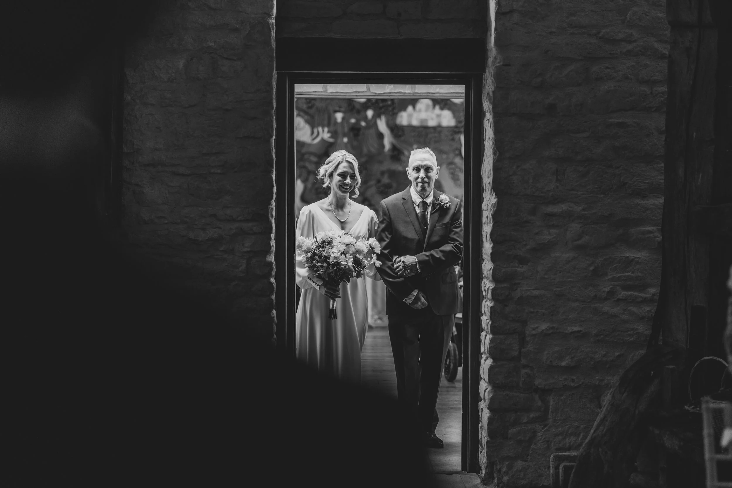 Bride and father standing at doorway of Owlpen Manor, ready to walk down the aisle