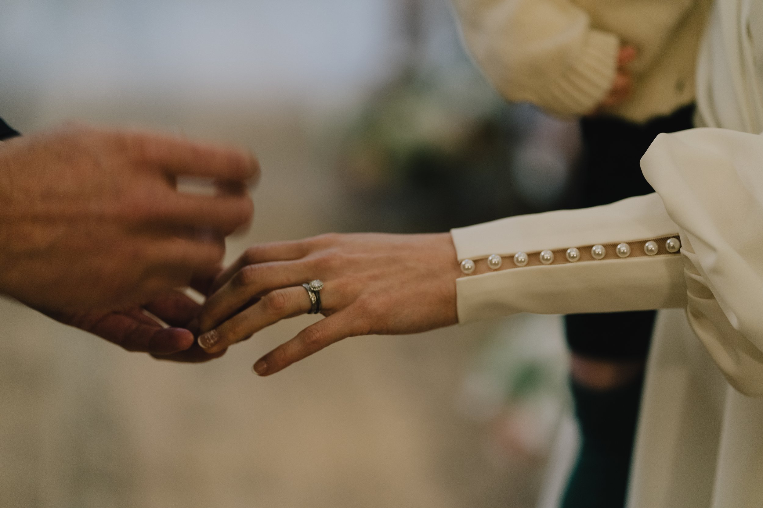 Groom placing wedding ring on bride’s finger during ceremony at Owlpen Manor