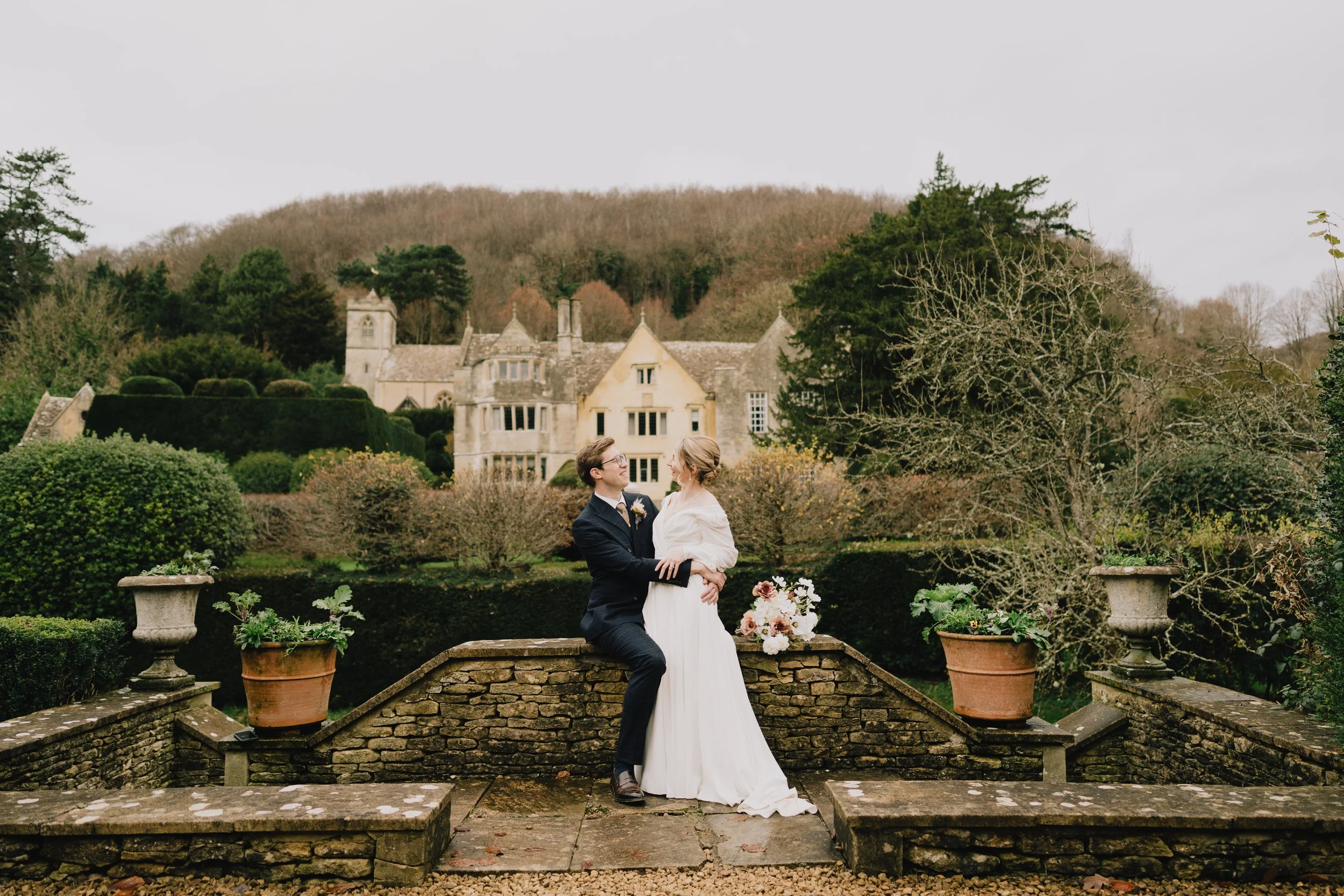 Bride and groom posing with the historic Owlpen Manor house in the background