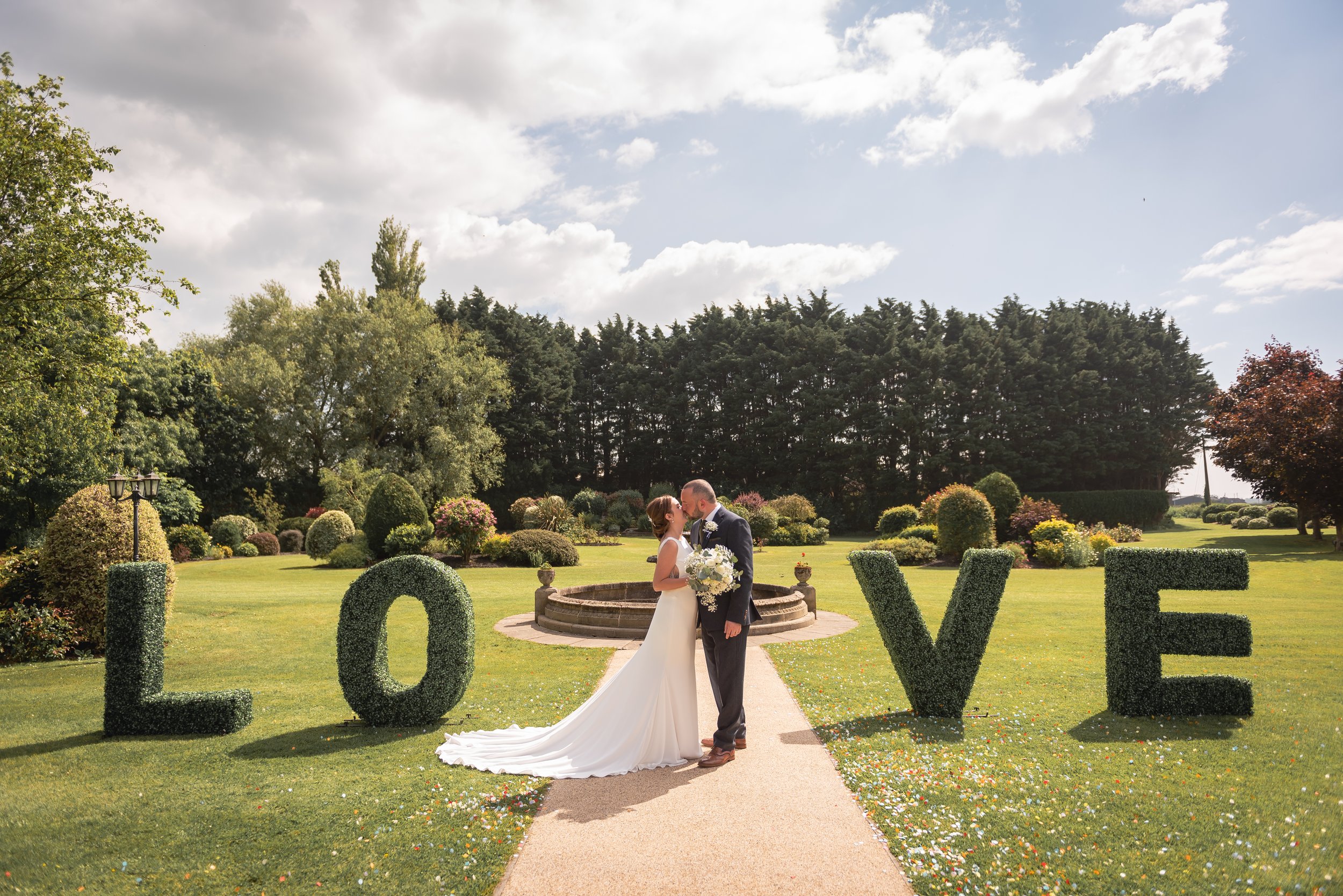 Bride and Groom kissing outside the large love letters on the green at Batch Country House in Weston-super-Mare