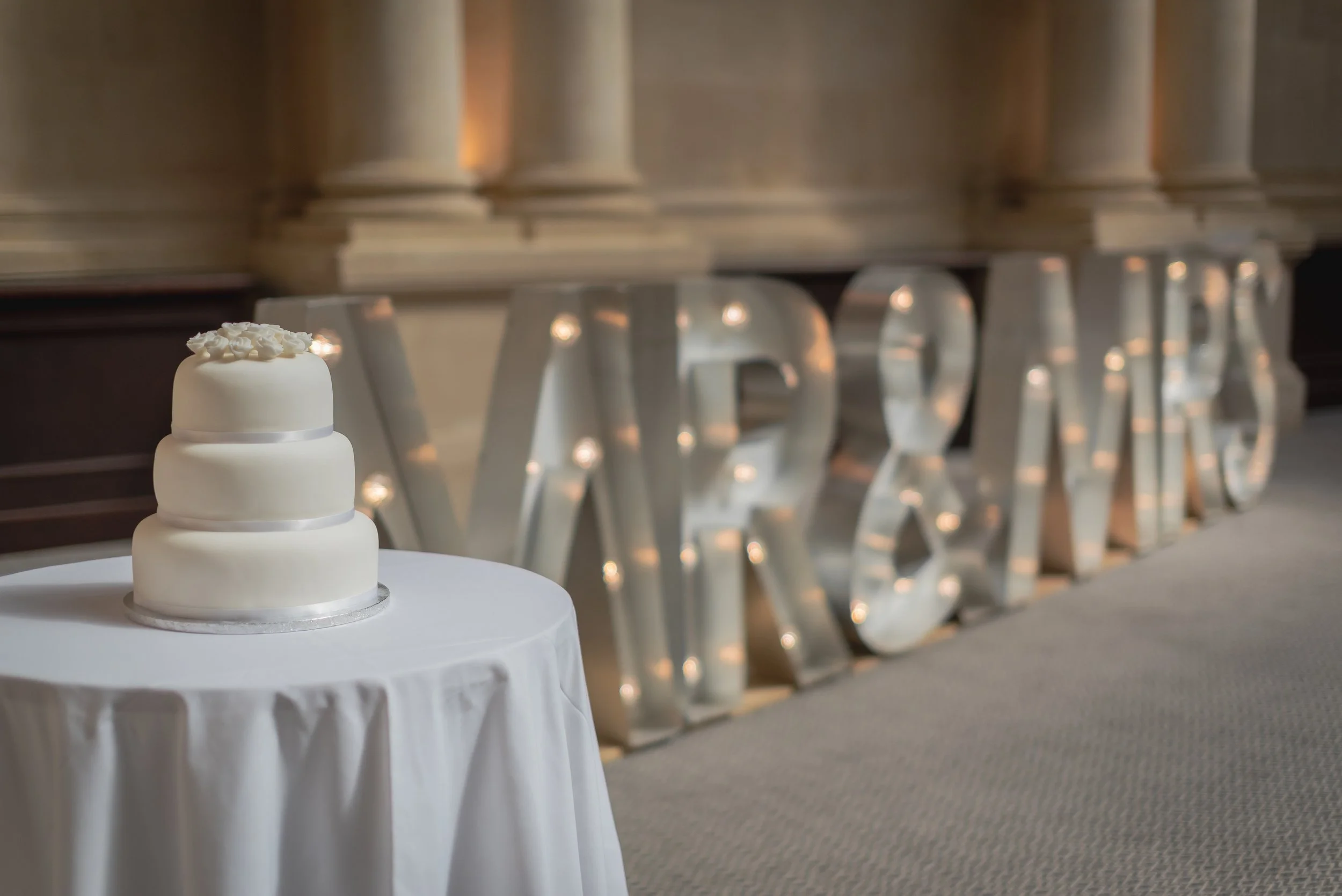 Wedding cake situated in front of LOVE light sign