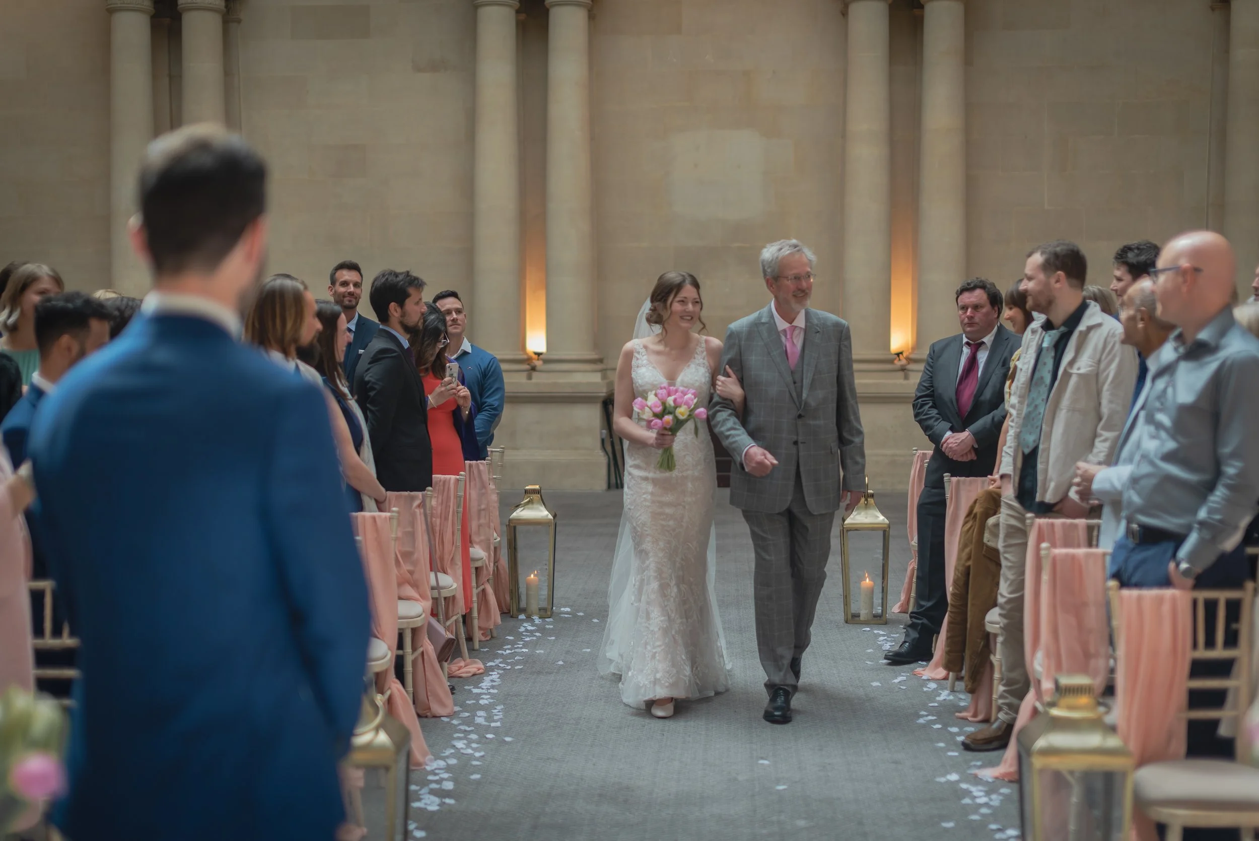 Bride and Father of the Bride walking down aisle with guests looking on