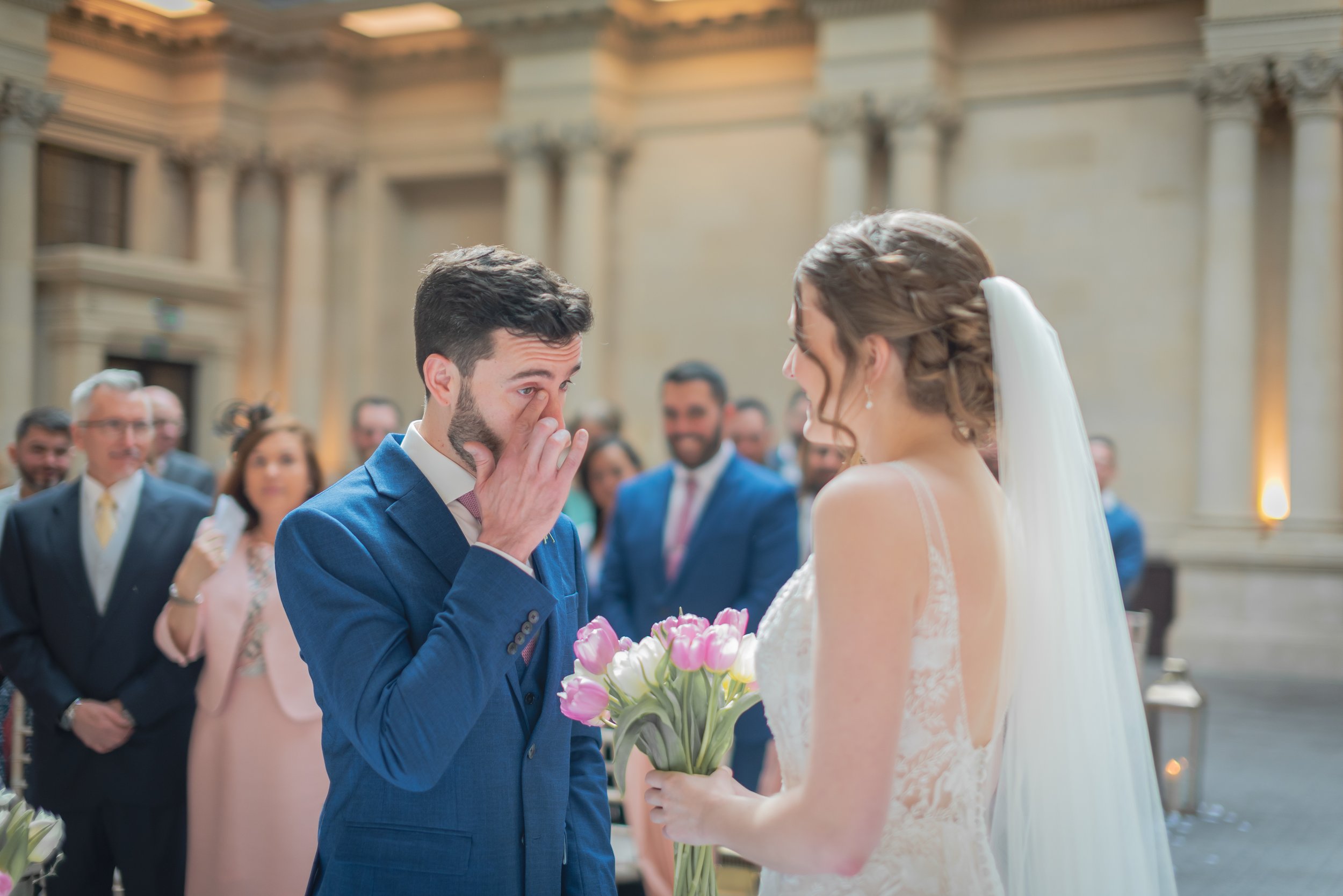 Groom wiping away a tear as the bride approaches him