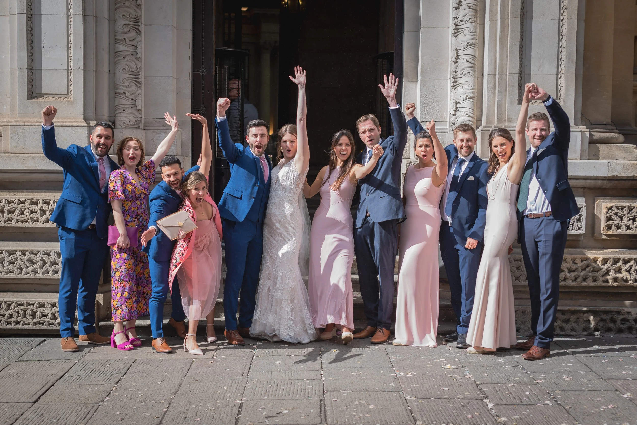 Bridesmaids and Groomsmen cheering with hands in the air after getting married