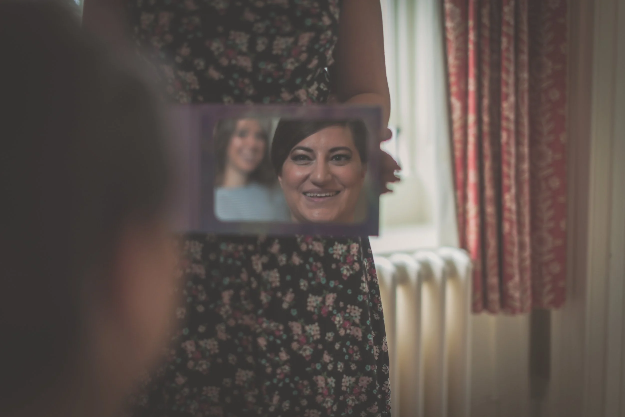 Bride looking into the mirror after having her make up done during the prep for her wedding at Aldwick Estate