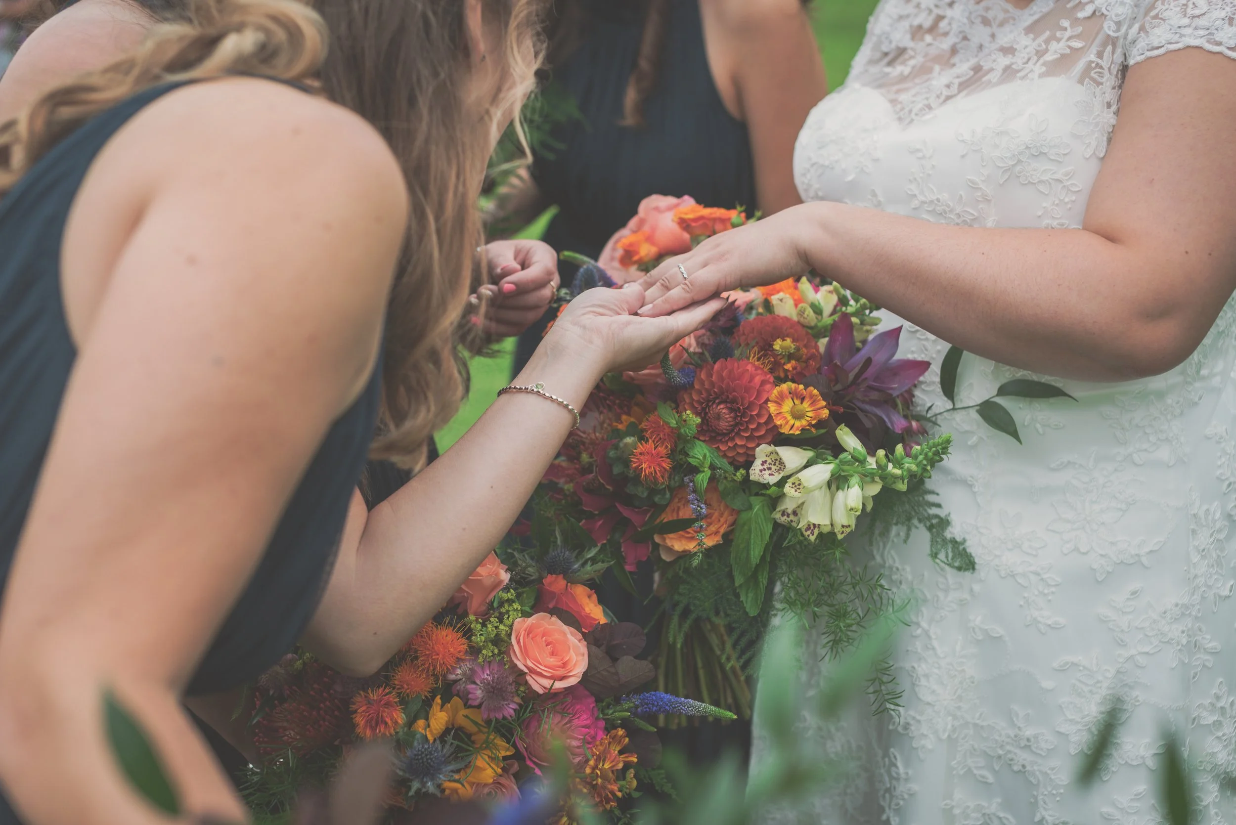 Bridesmaids gazing at the brides ring surrounded by wedding flowers