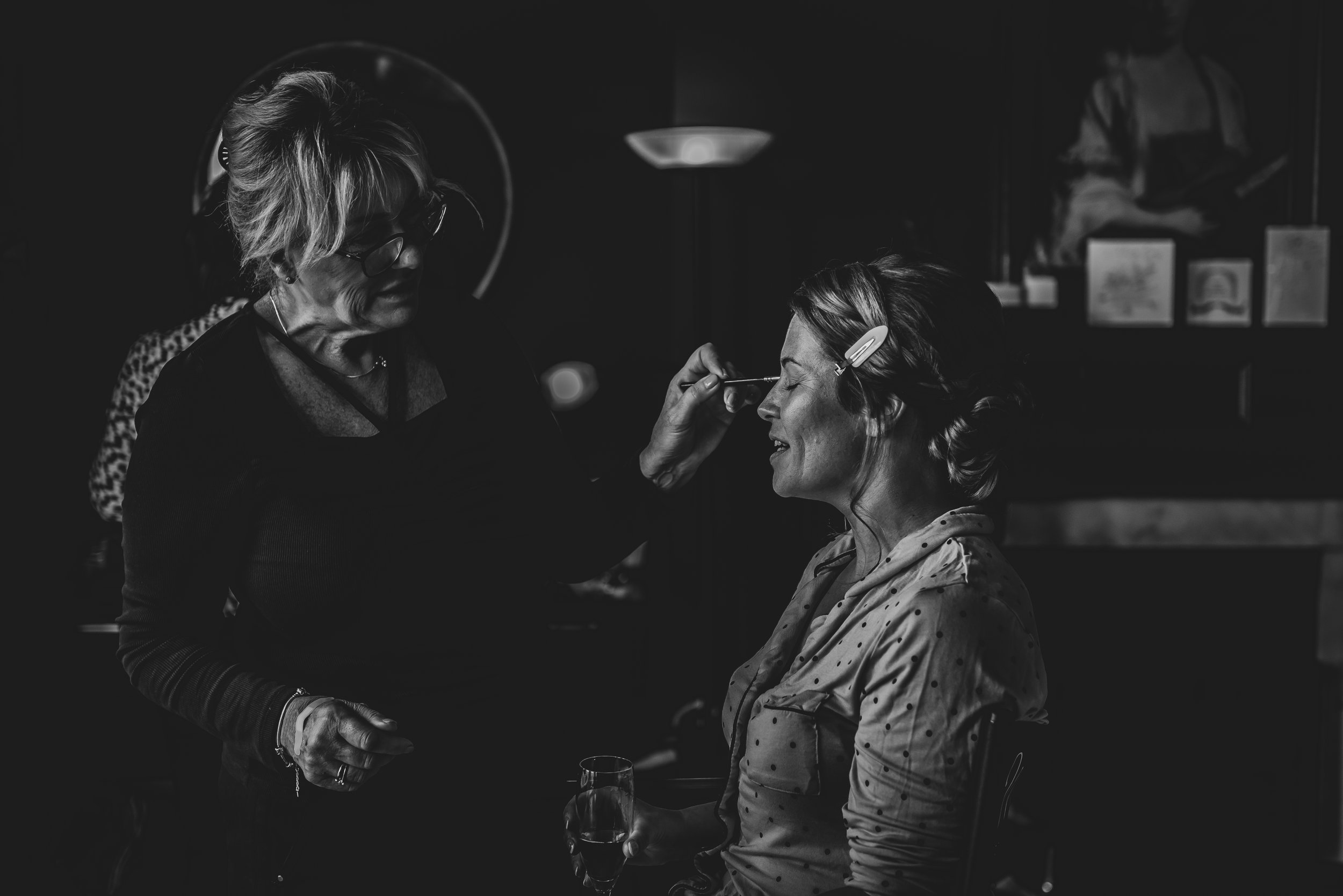 Candid black and white photo of bride having makeup done