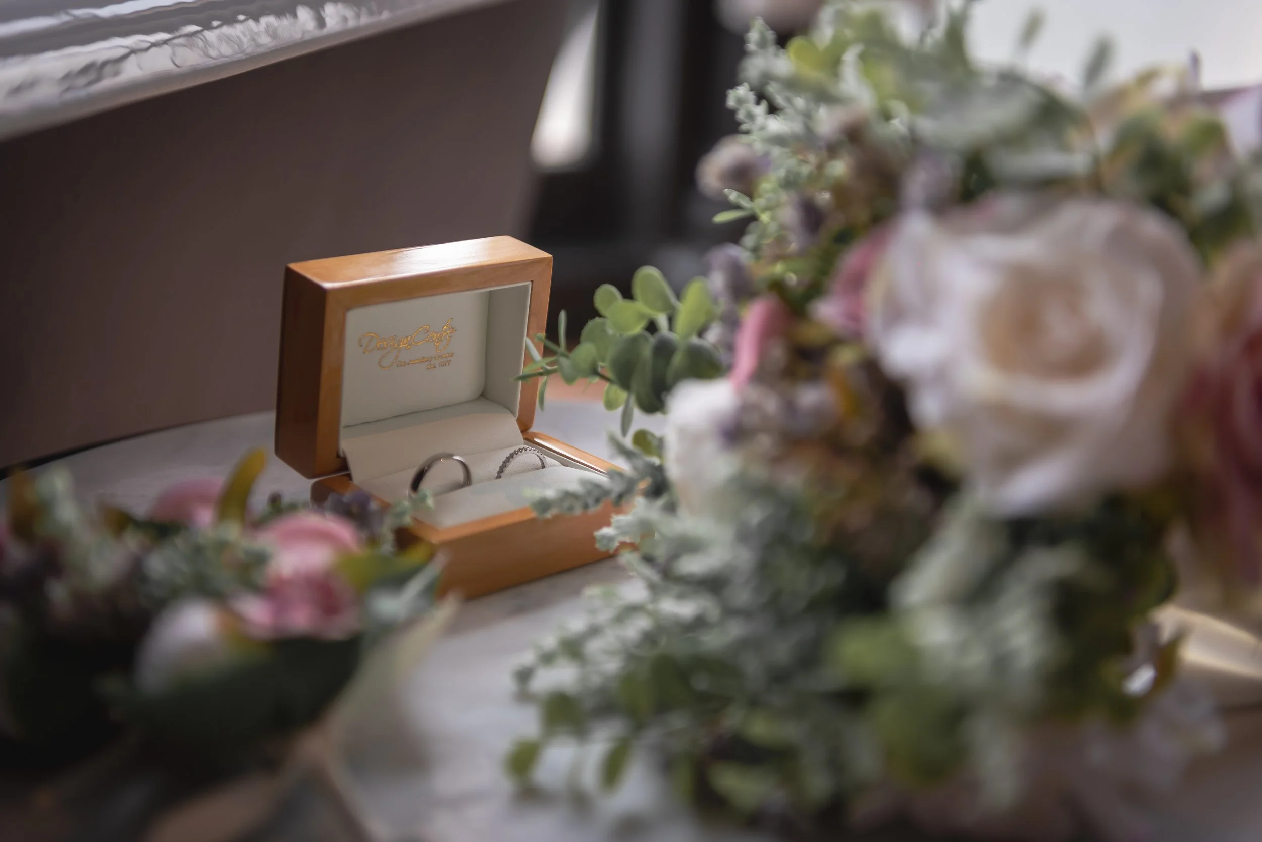 Close-up of wedding rings and floral bouquet on morning of wedding