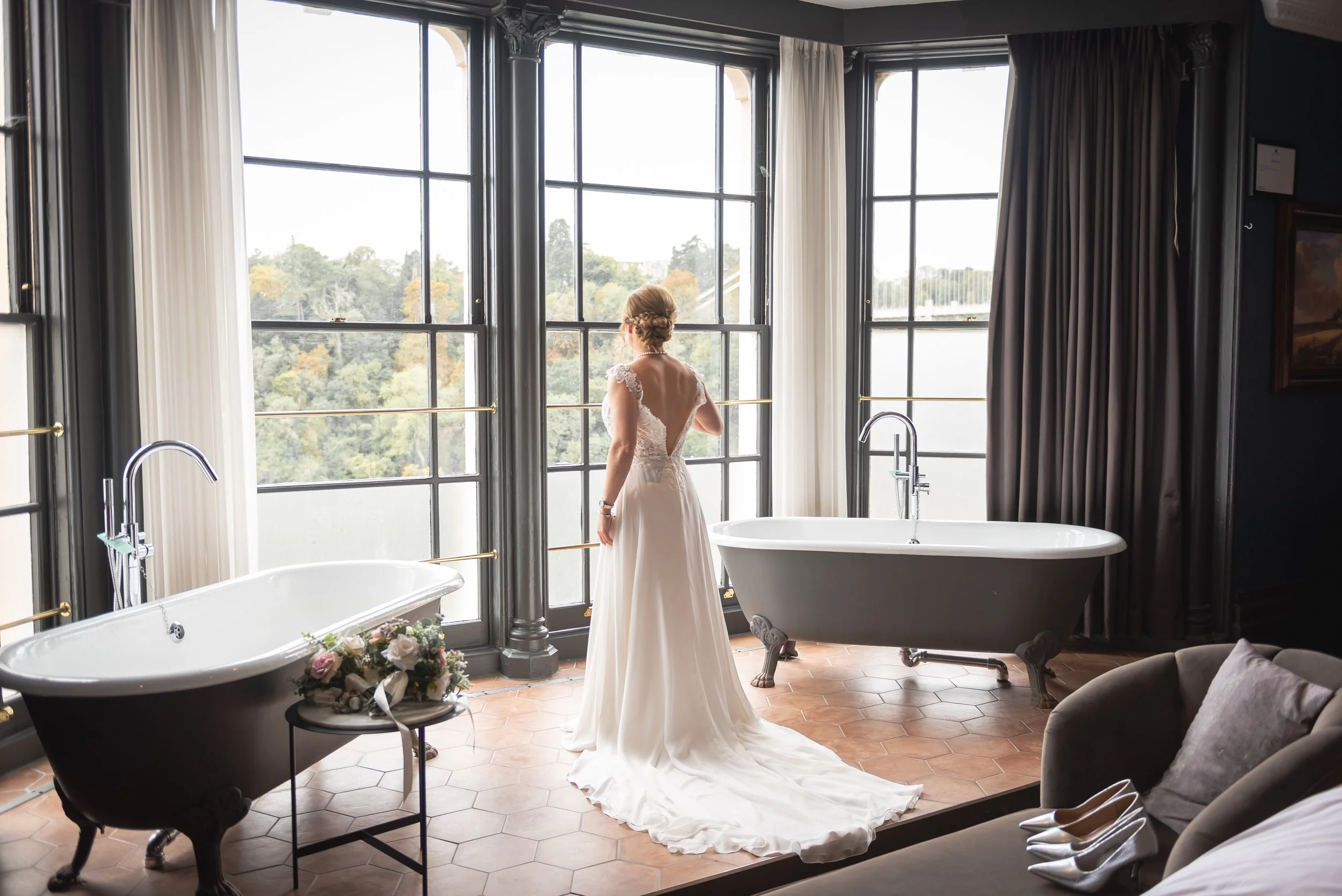 Bride standing by large windows and roll-top bath in Avon Gorge Hotel suite