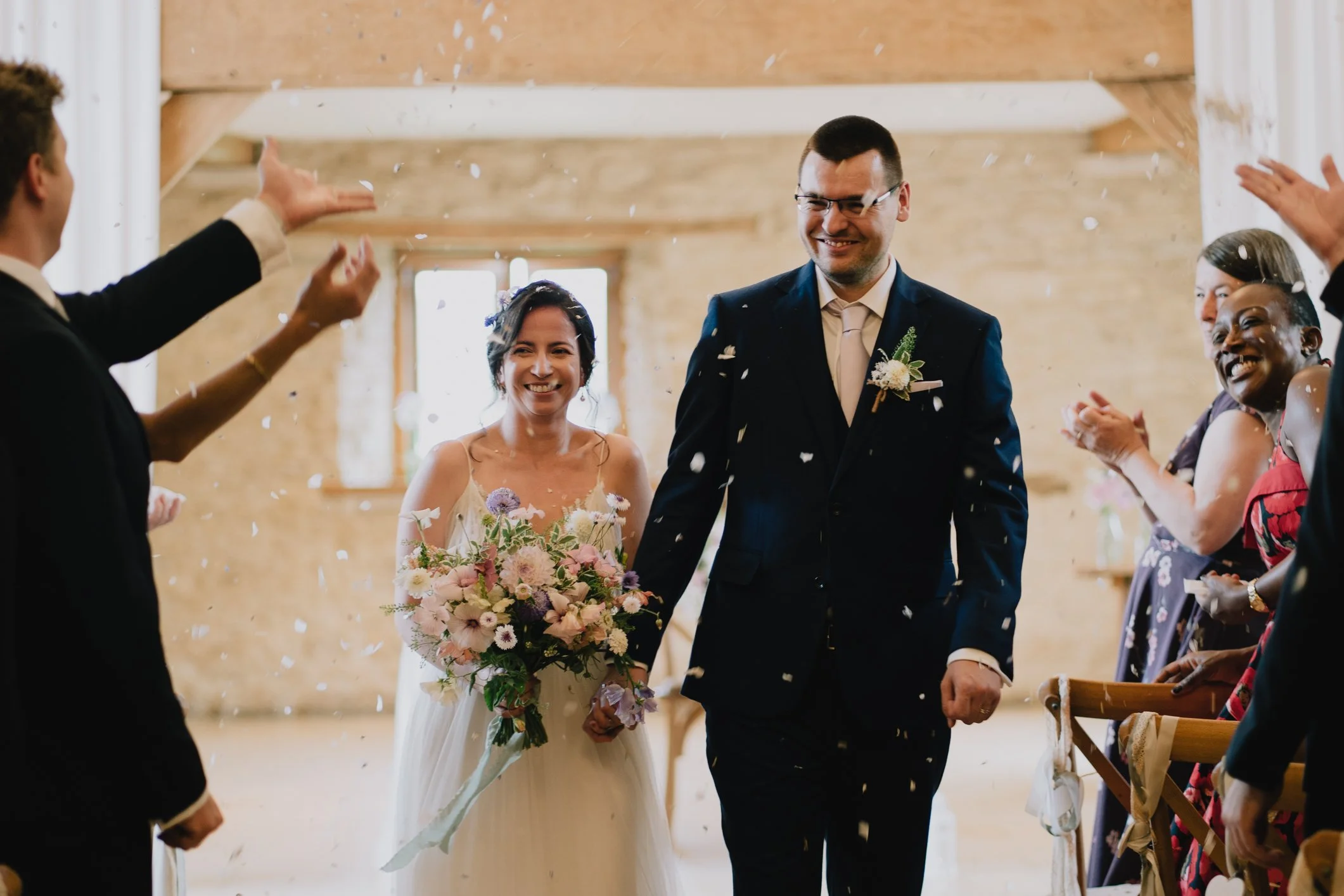 Bride and Groom embrace the confetti aisle at Kingscote Wedding Venue in Tetbury near Gloucester