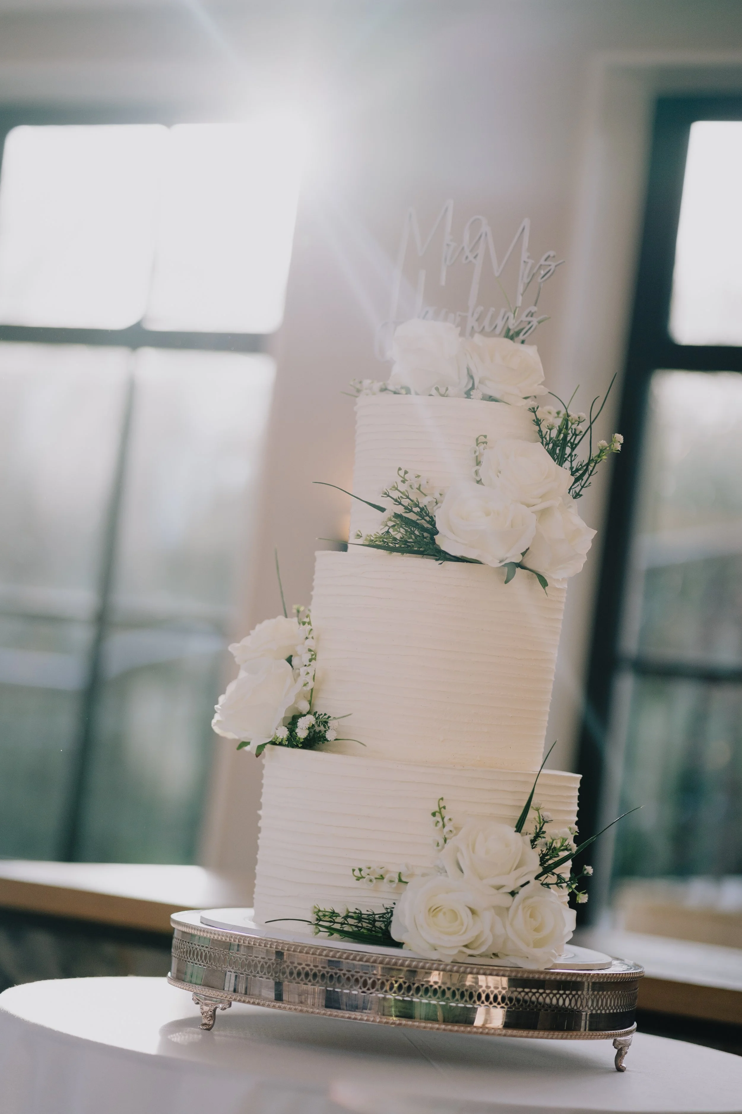 Beautiful wedding cake with a sun flare glistening down at The Pear Tree in Purton ready for the wedding