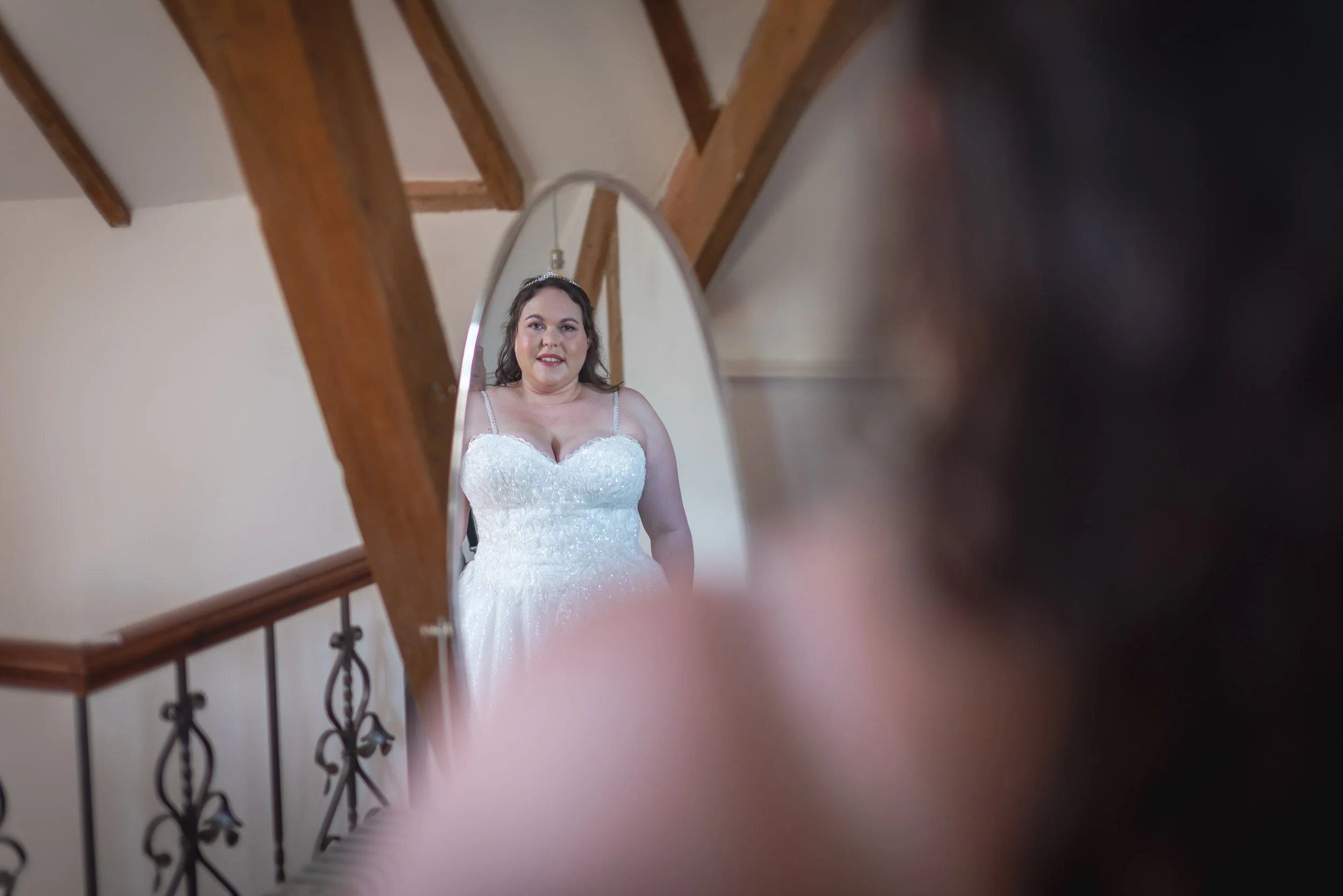 Bride putting dress on looking in a mirror at Deer Park Hall