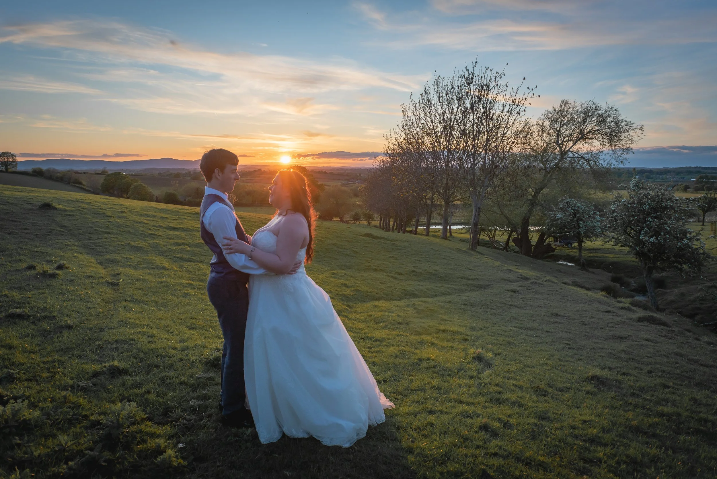 Sunet in background with bride and groom in foreground at Deer Park Hall in Cotswolds