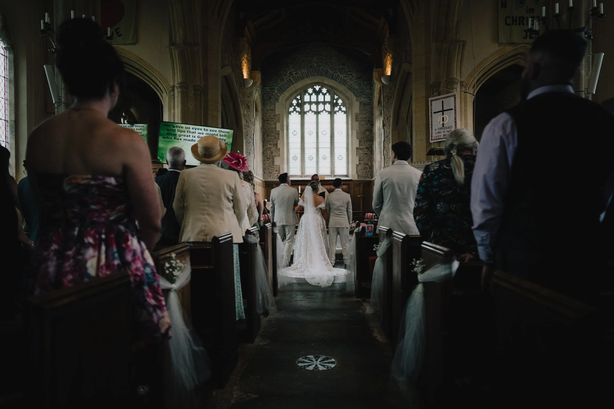 Bride and groom standing together at the top of the aisle inside St John’s Church Radstock during wedding ceremony