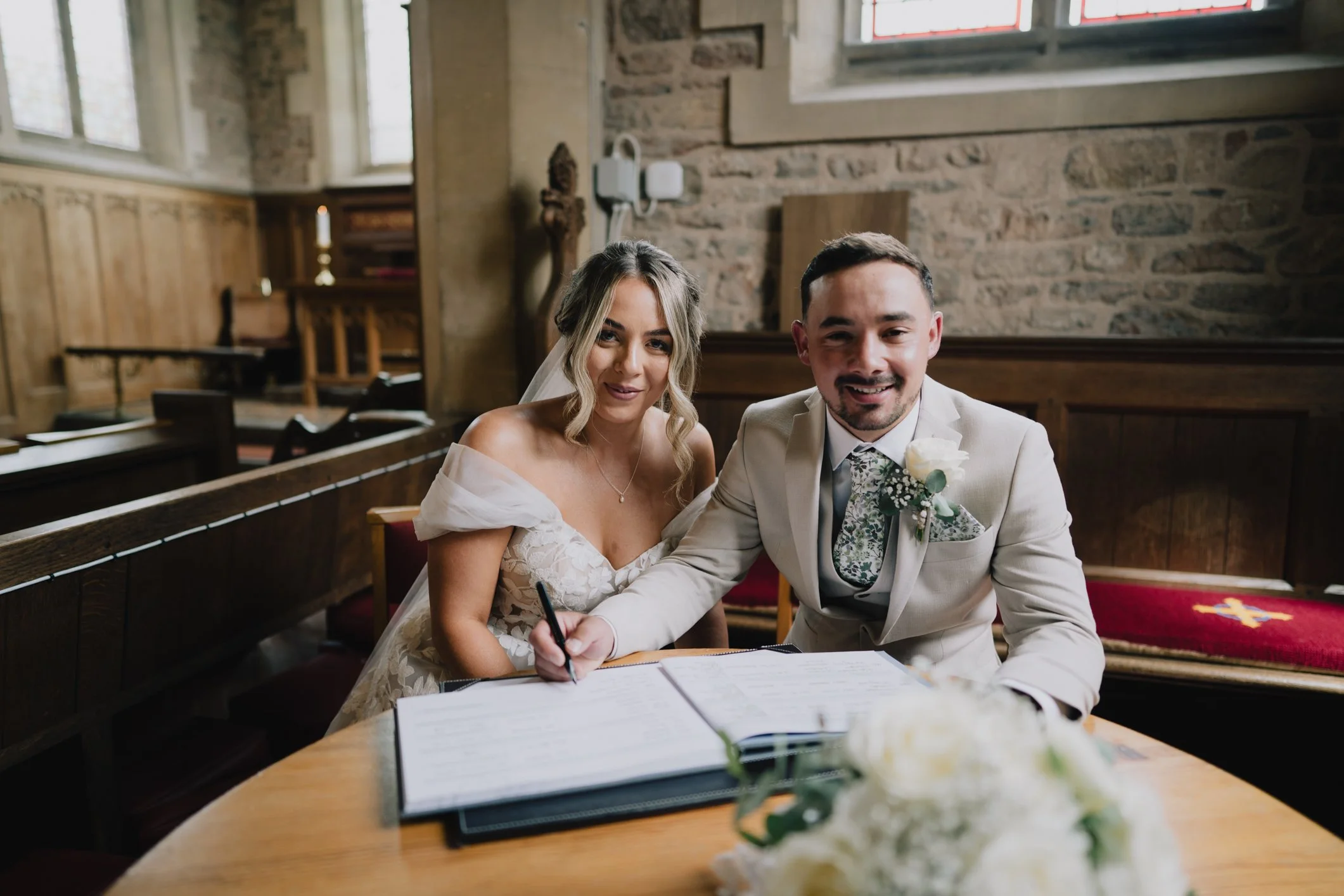 Bride and groom signing the register inside St John’s Church Radstock after their wedding ceremony