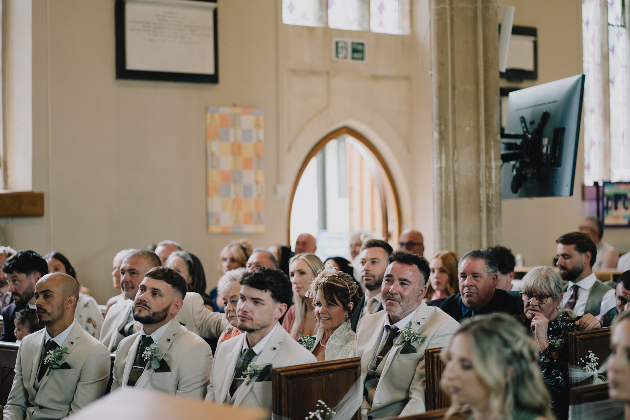 Wide angle photo of wedding guests inside St John’s Church Radstock, Somerset, during ceremony