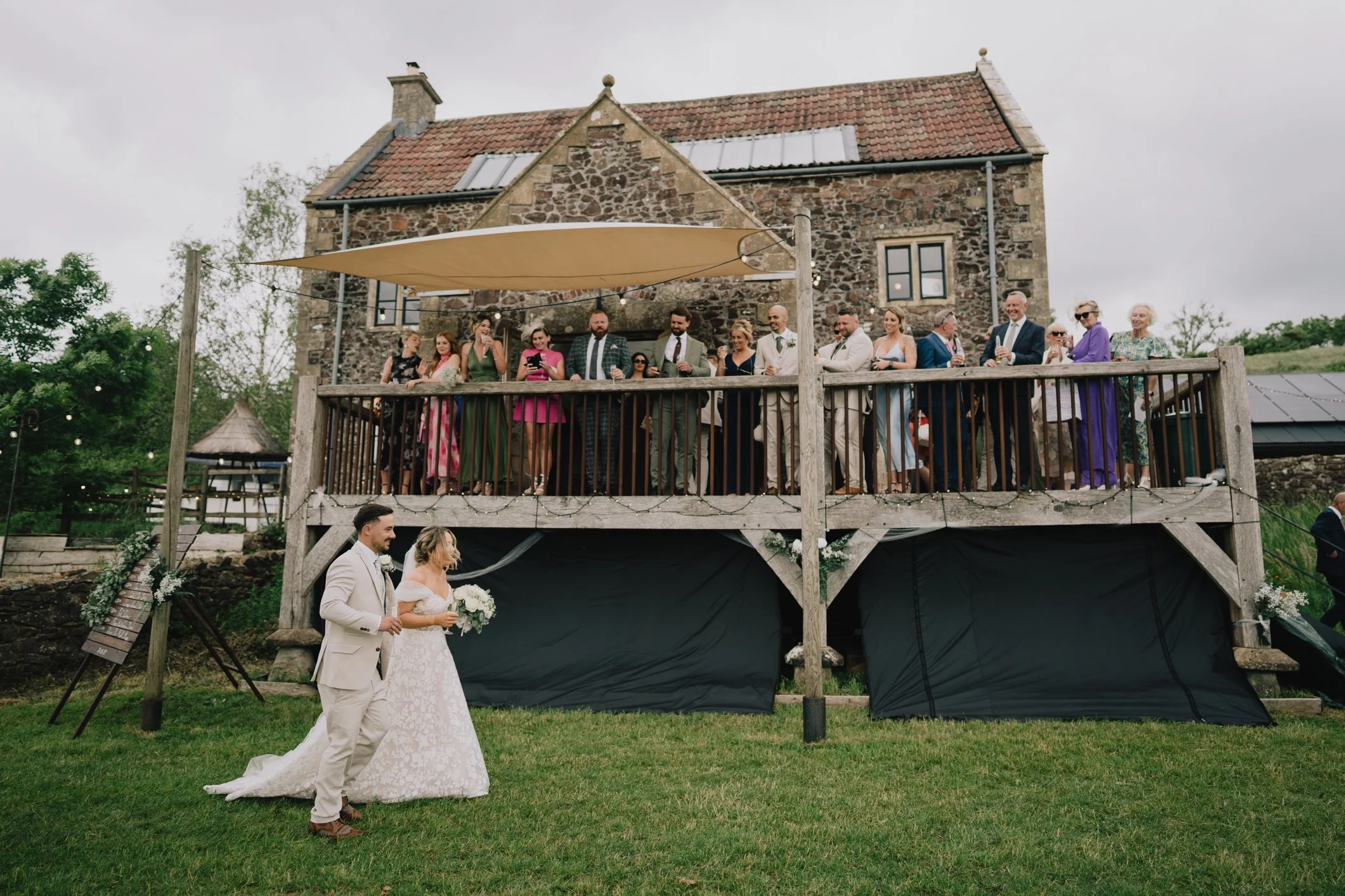 Bride and groom arriving at Lapwing Farm wedding reception, welcomed by cheering guests in Somerset countryside