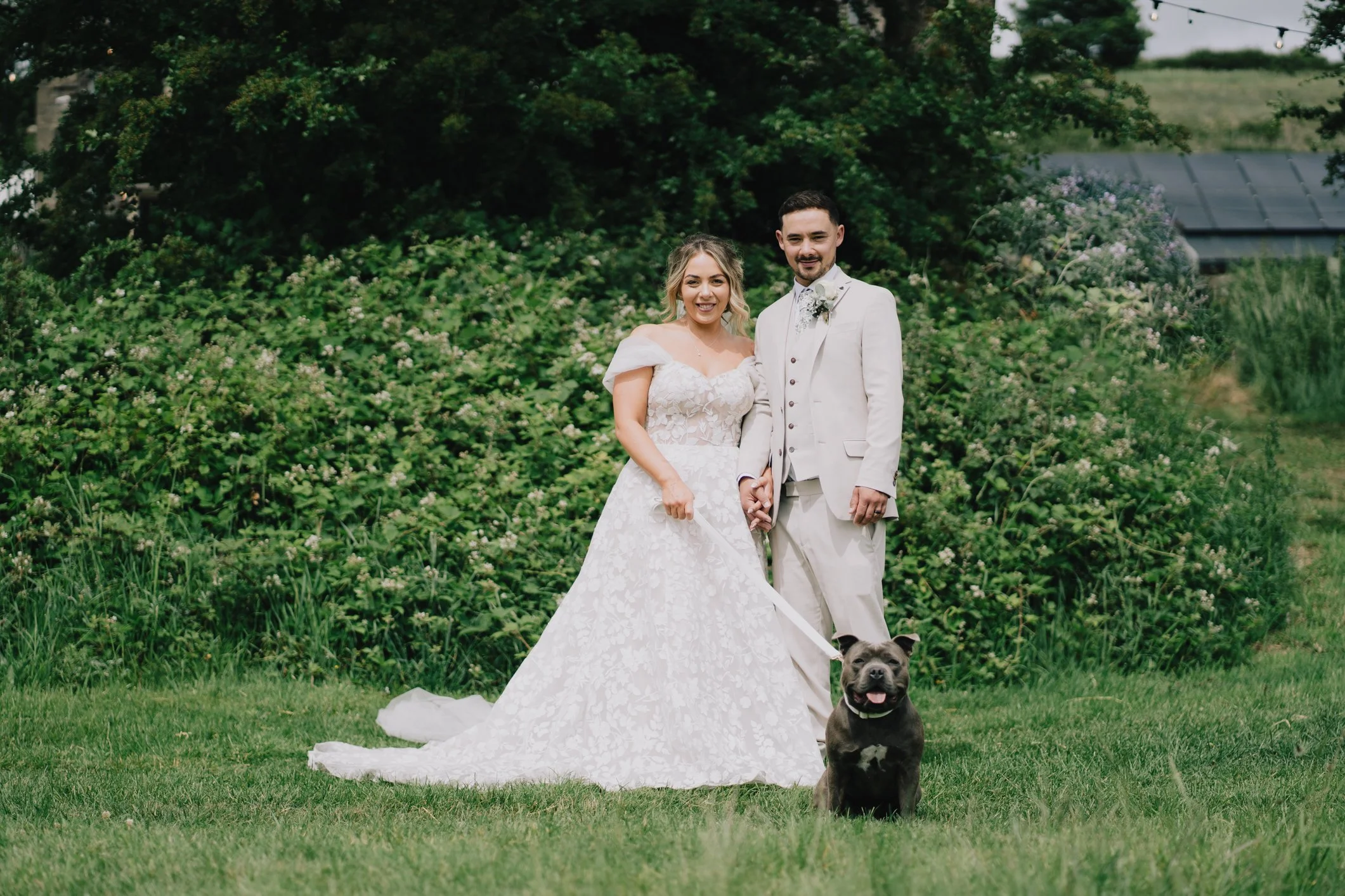 Natural wedding photo of bride and groom with their dog at Lapwing Farm, fun and relaxed moment including their pet on the wedding day