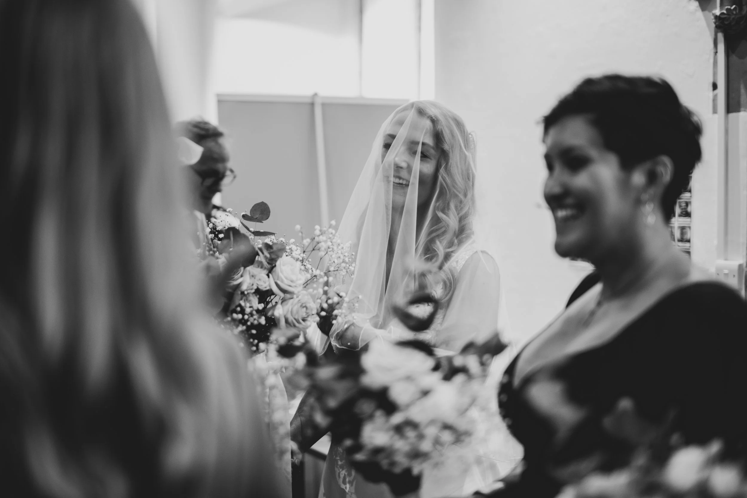 Black and white photo of a bridal shower or gathering, with smiling women exchanging flowers and celebrating after getting ready before her Bristol wedding.