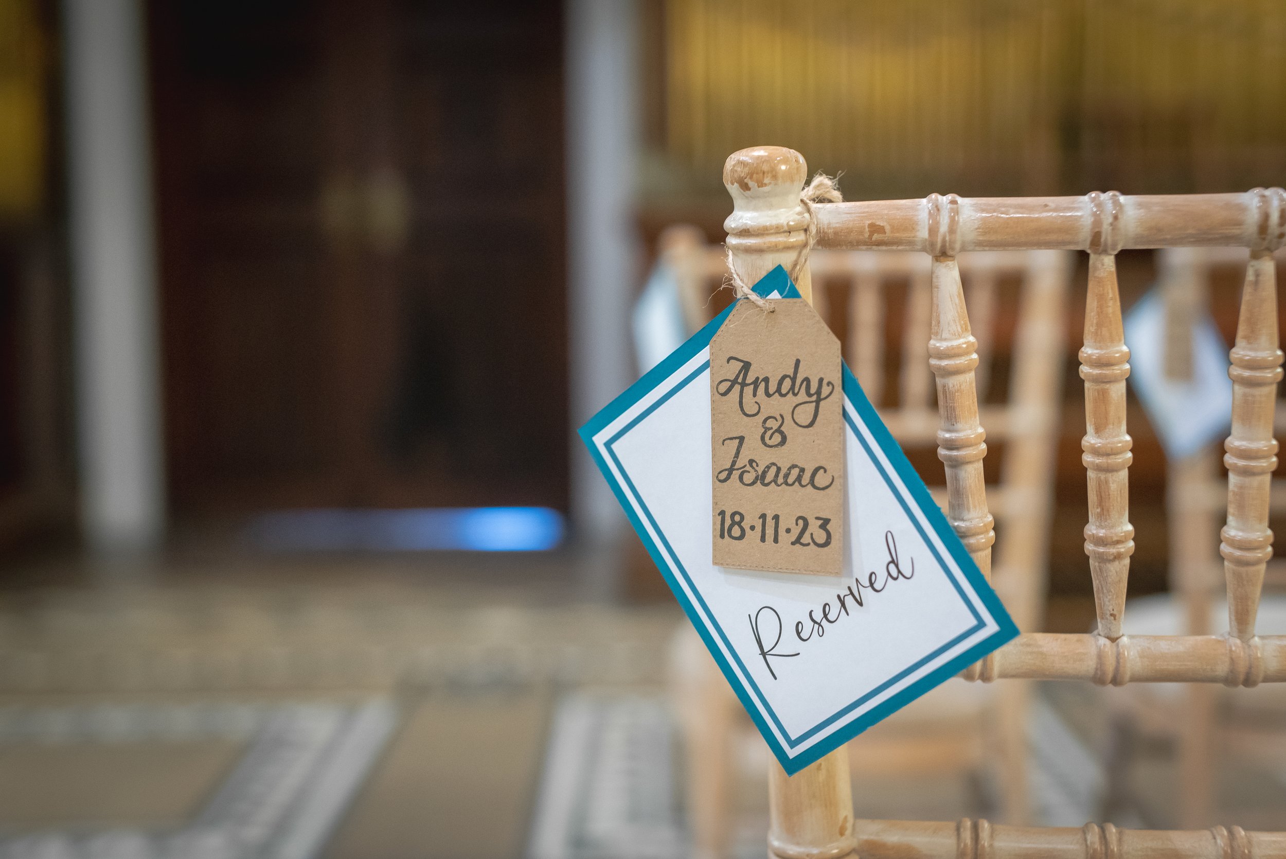 Close-up of a "Reserved" sign on a wooden chair in the elegant ceremony room at Leigh Court.