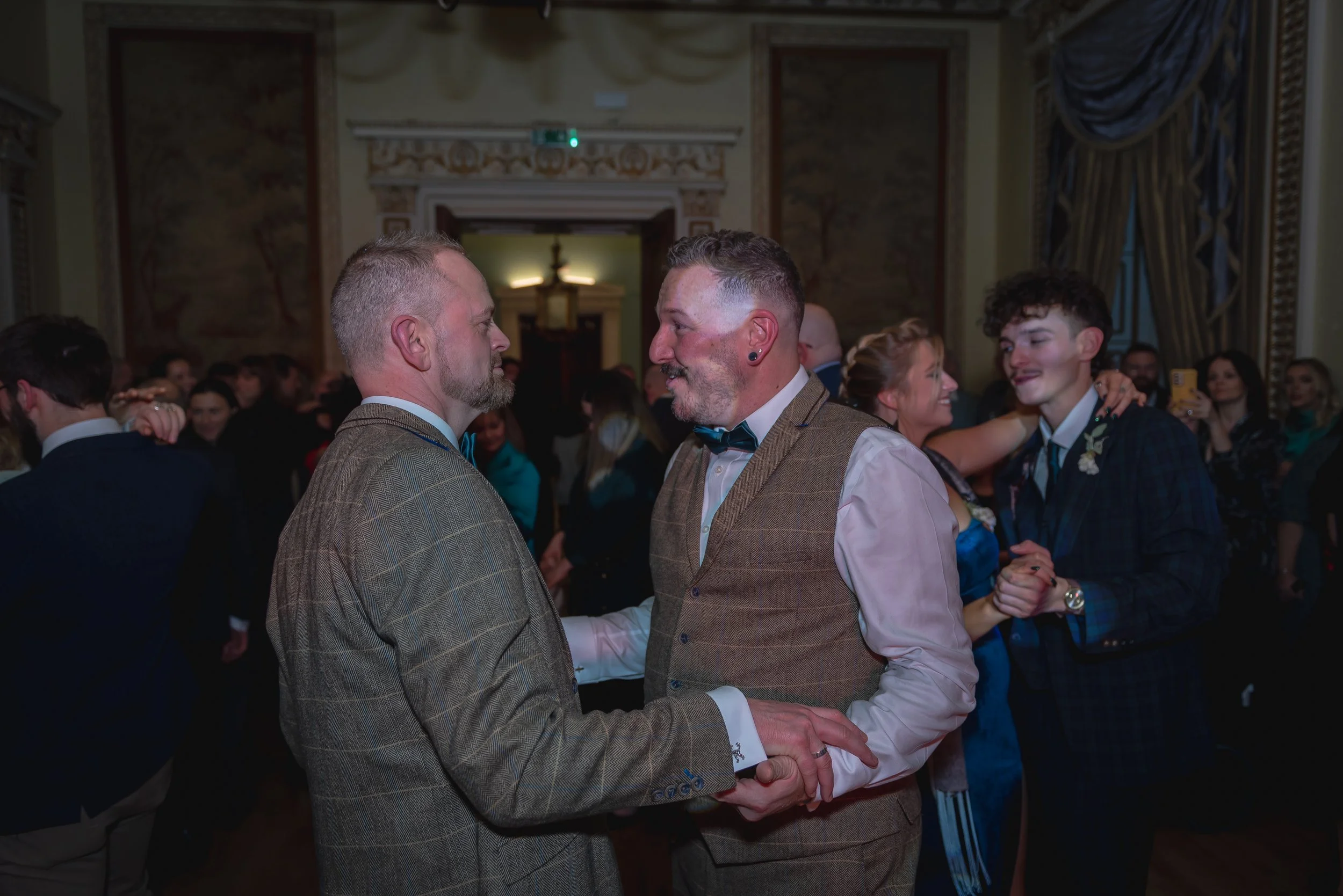 Andy and Issac sharing their first dance as a married couple, surrounded by warm light and smiling faces.
