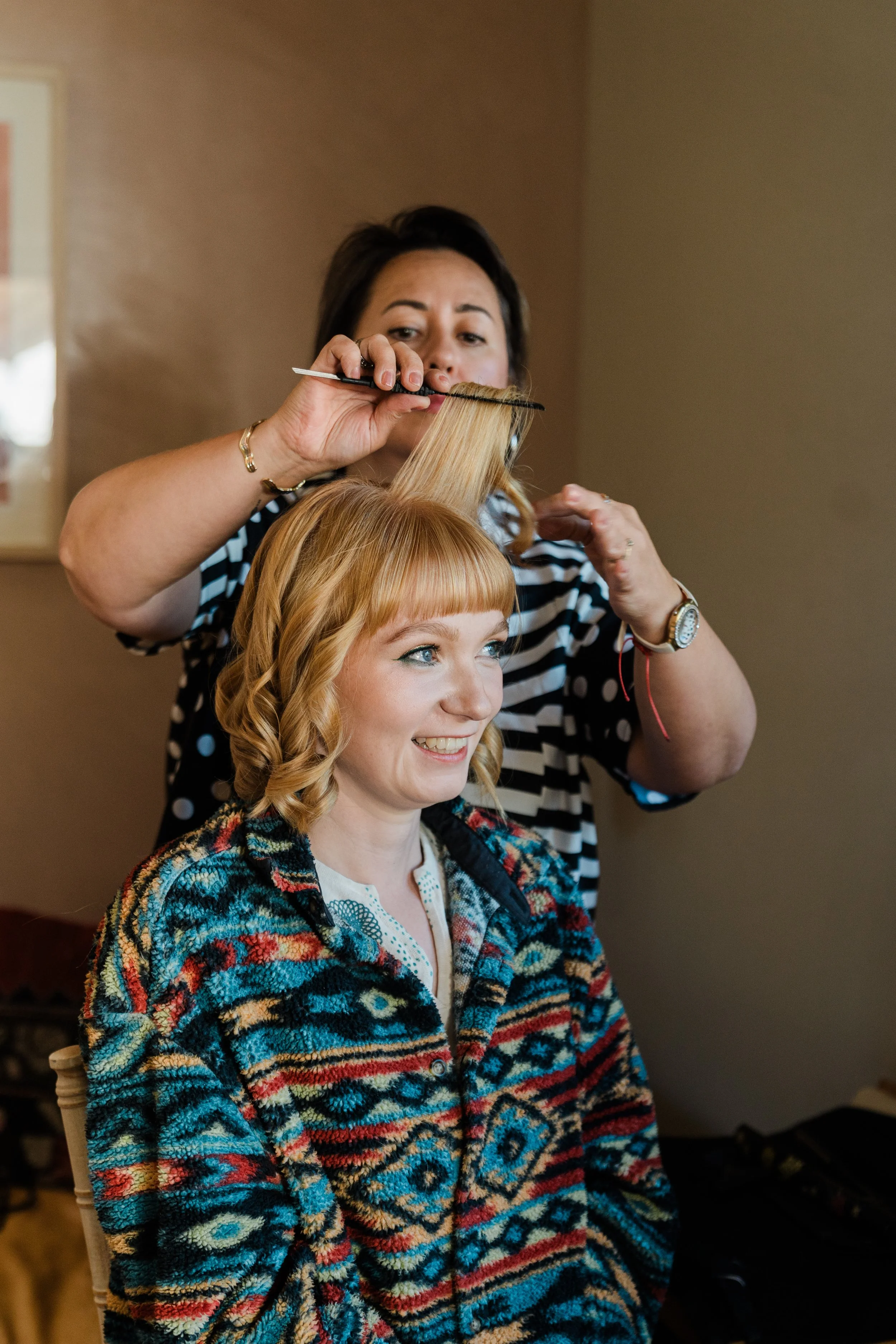 Teh bride styling a young girl’s hair with a brush inside a room at Lapwing Farm