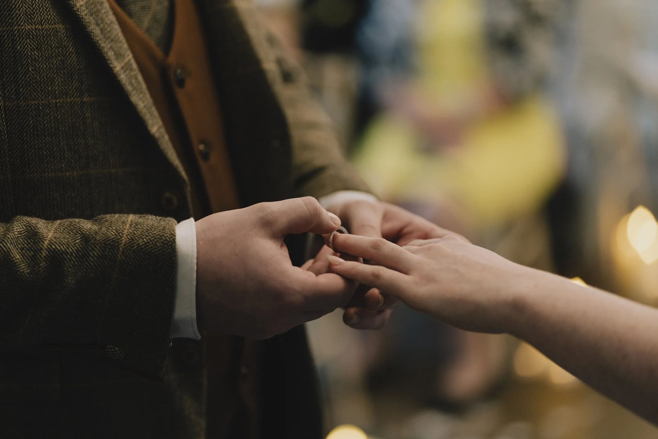 A Groom is placing a ring on their brides finger during a wedding ceremony.