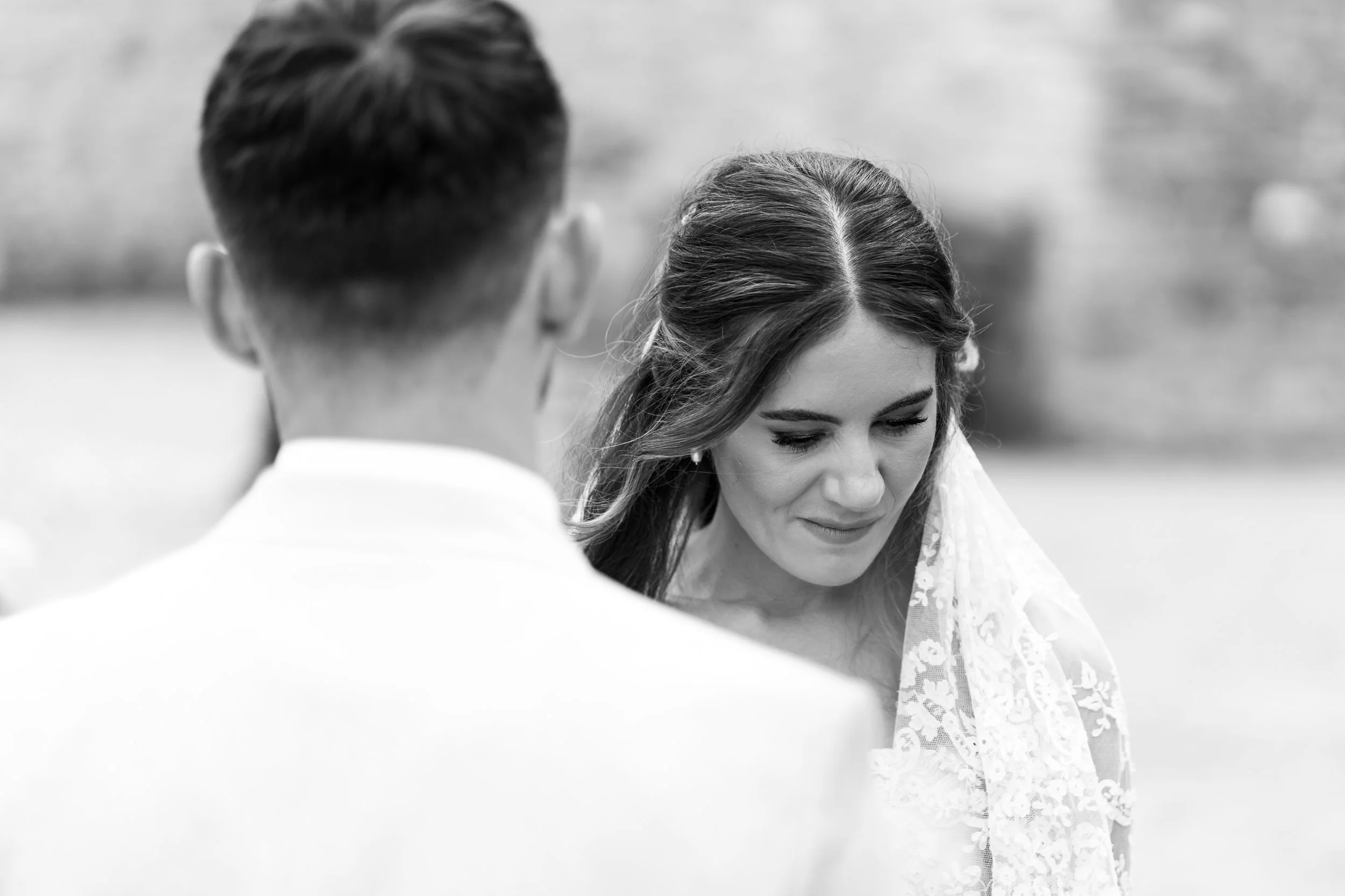 Black-and-white photo of a couple, with a woman with long hair and a man with short hair, viewed from behind, in an outdoor setting.
