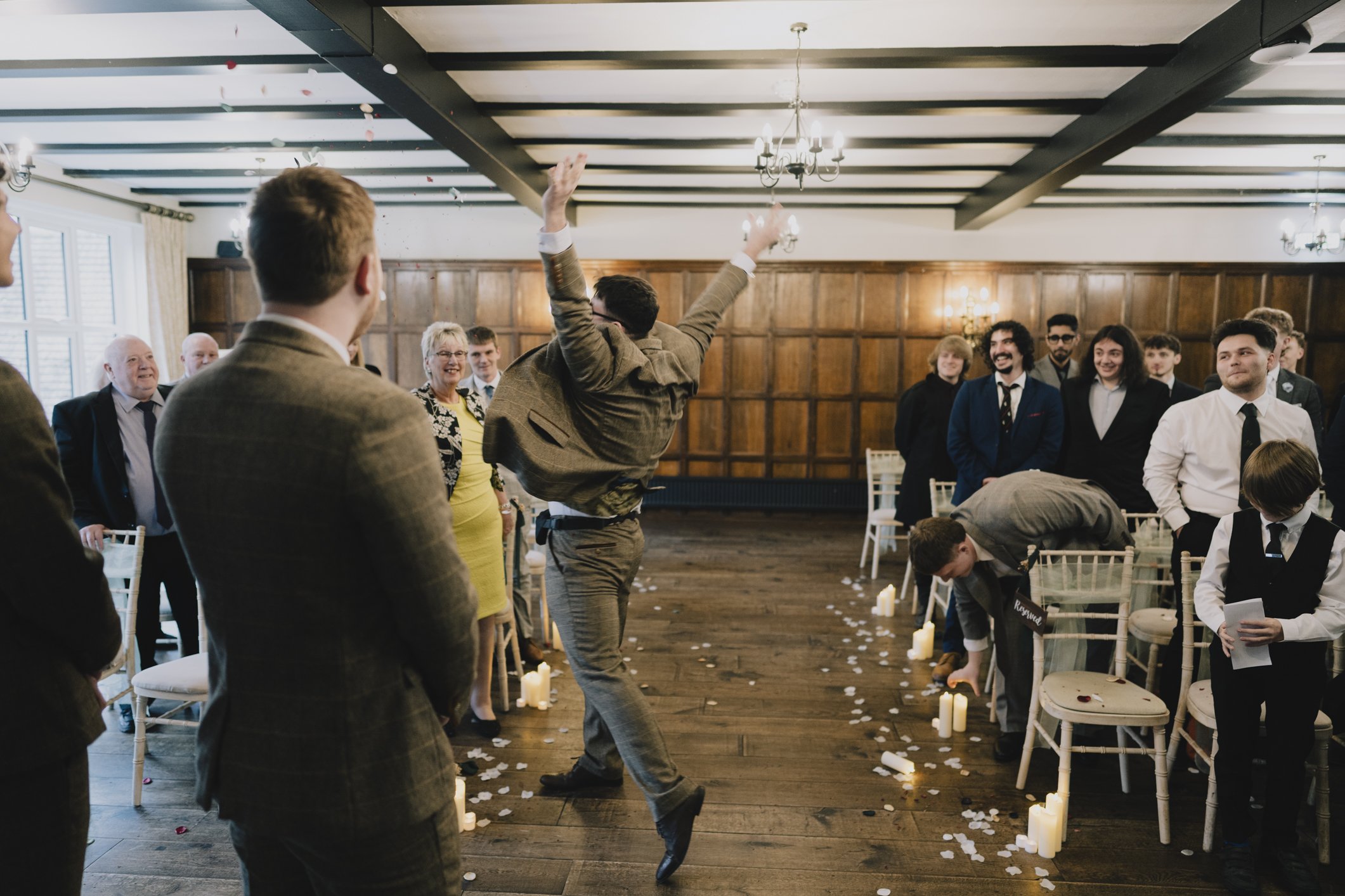 Flower boy dancing energetically in a suit at a wedding reception at Webbington, with guests watching and smiling.