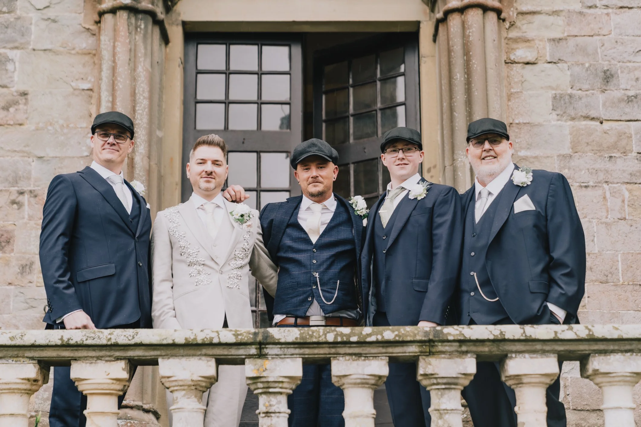 Grooms in peaky blinders style hats outside Clearwell Castle