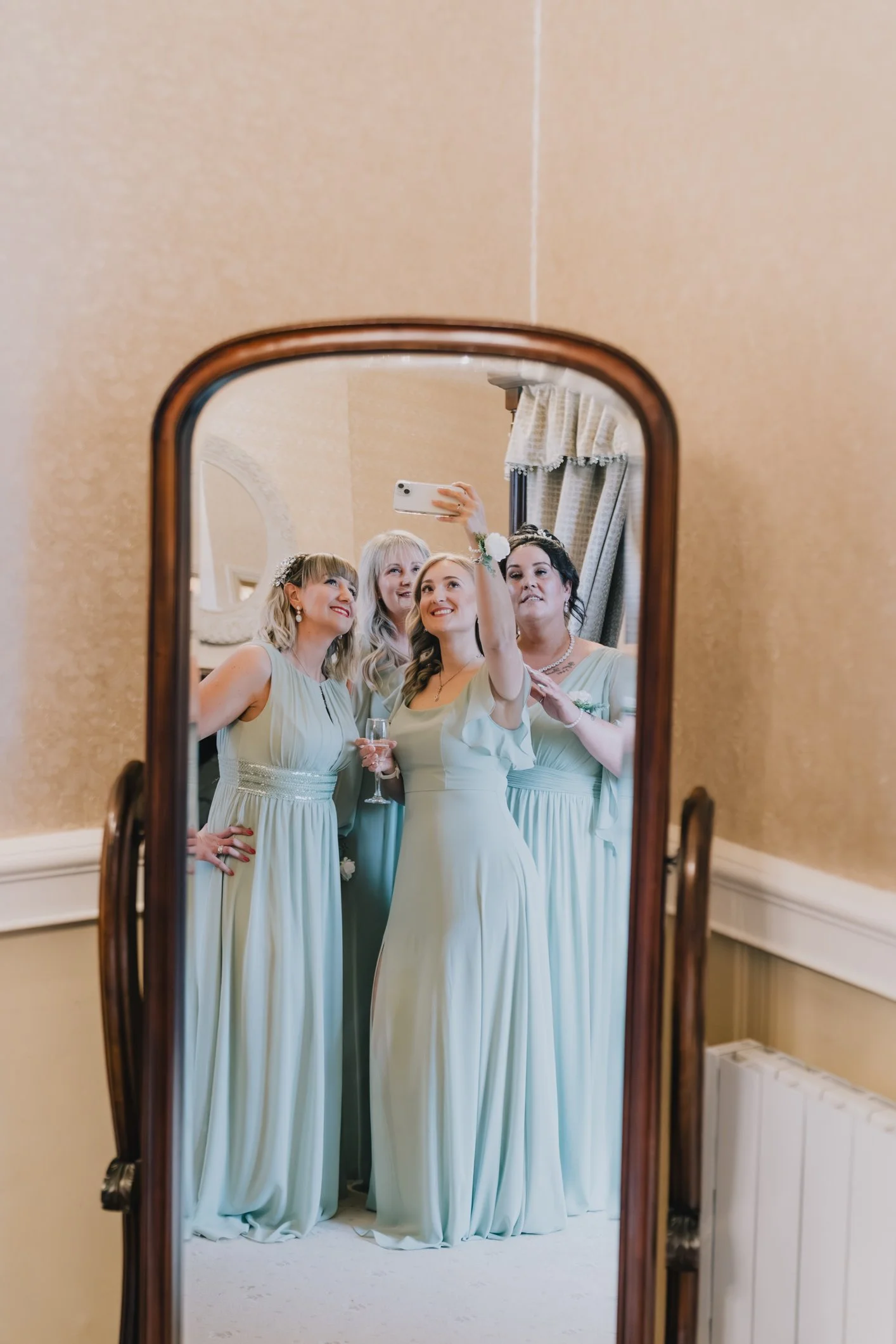 Bridesmaids taking a selfie in front of the mirro at the prep room in Clearwell Castle