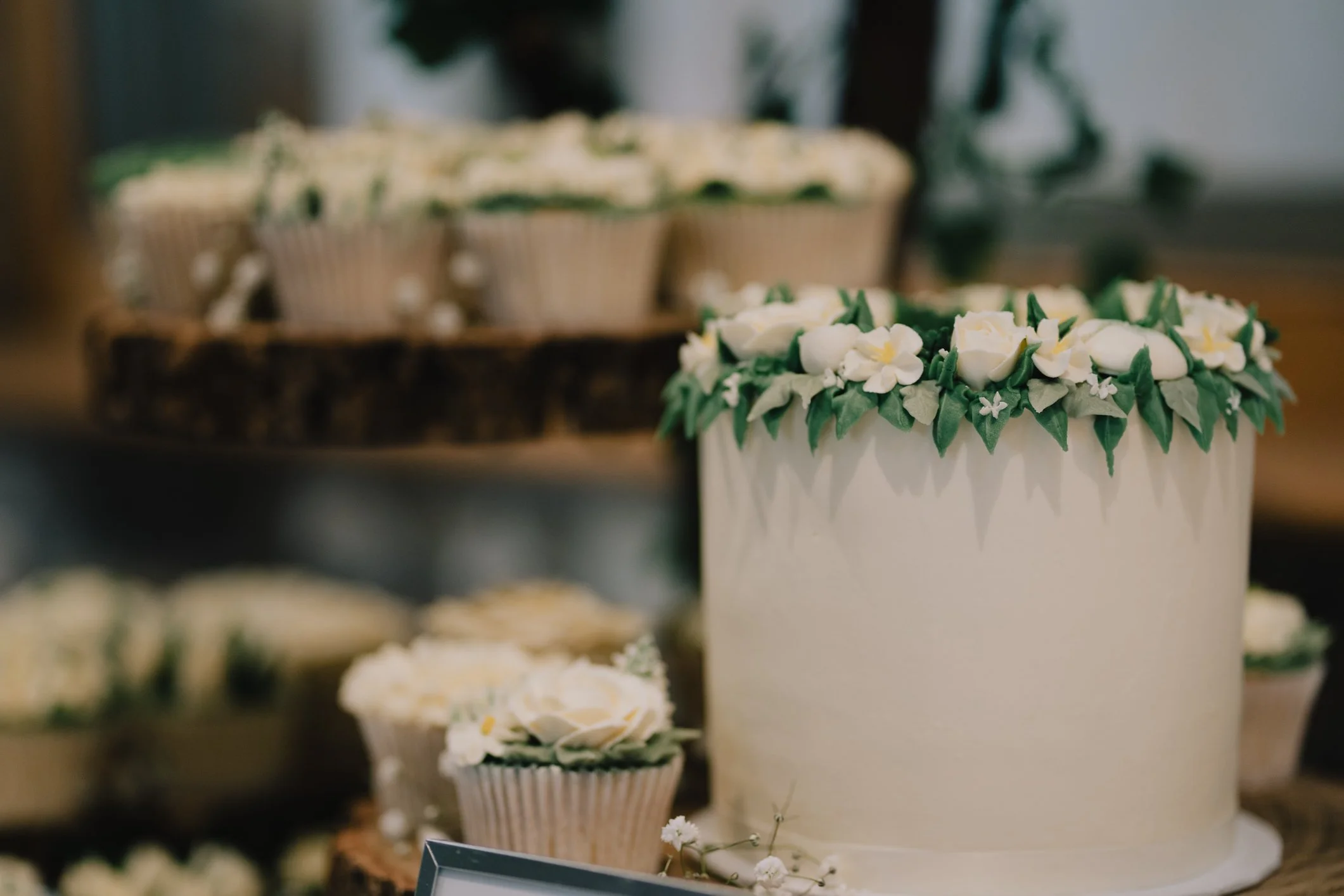 A display of decorated cupcakes with white and green frosting on a table at a celebration or event.