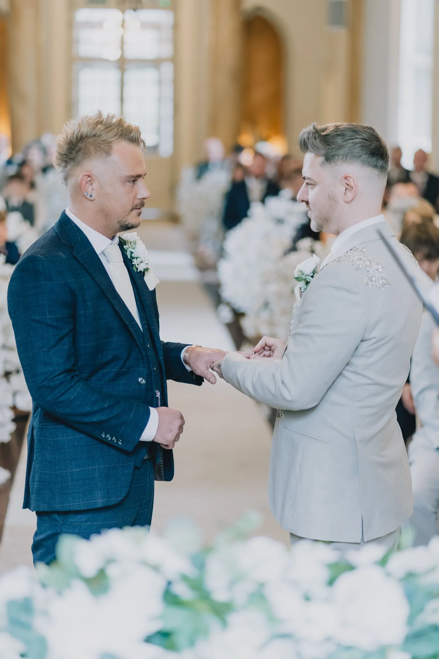 Grooms hold hands during love is love ceremony at Clearwell Castle